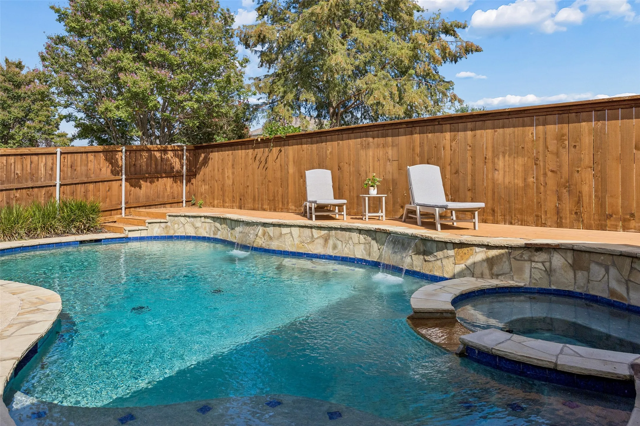 Poolside Space with Room to Lounge - A cedar deck runs alongside the pool, adding dedicated space for seating and sunning while the surrounding privacy fence and landscaping help create a more secluded backyard setting.
