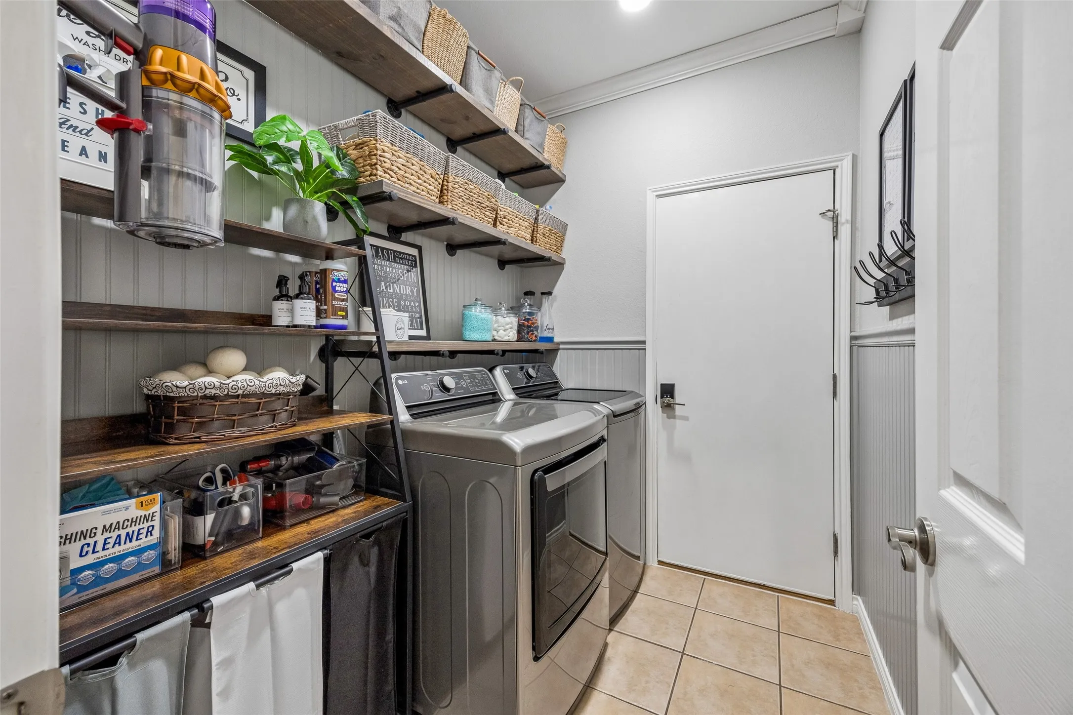 Laundry Room with Added Storage - Open shelving, wainscoting, crown molding, and a dedicated utility space make the laundry room practical, organized, and easy to use. The shelving was added as part of a 2026 laundry room upgrade.