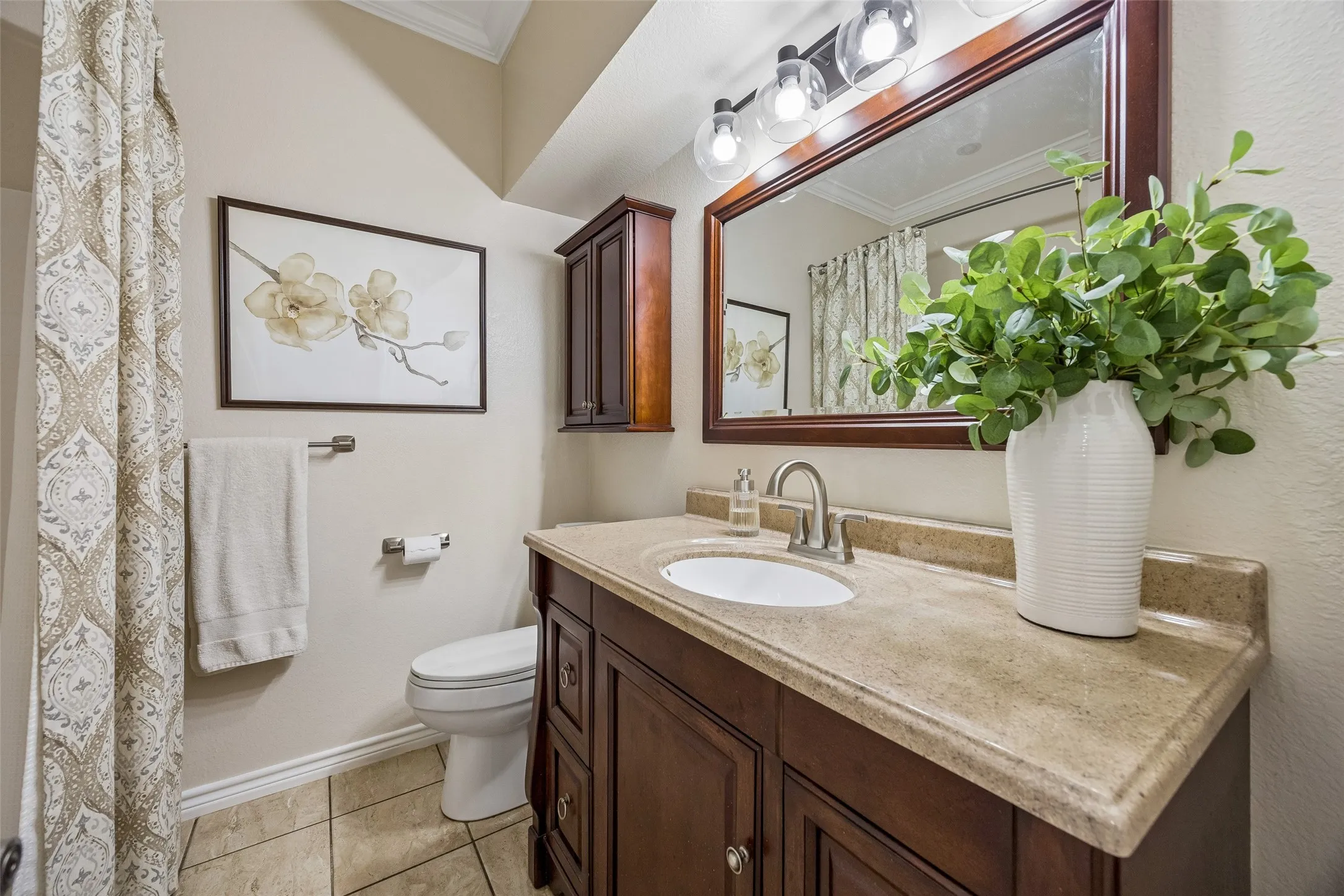 Updated Secondary Bath - The second bath features an updated vanity, stone-style countertop, framed mirror, updated lighting, and crown molding for a clean, finished look.
