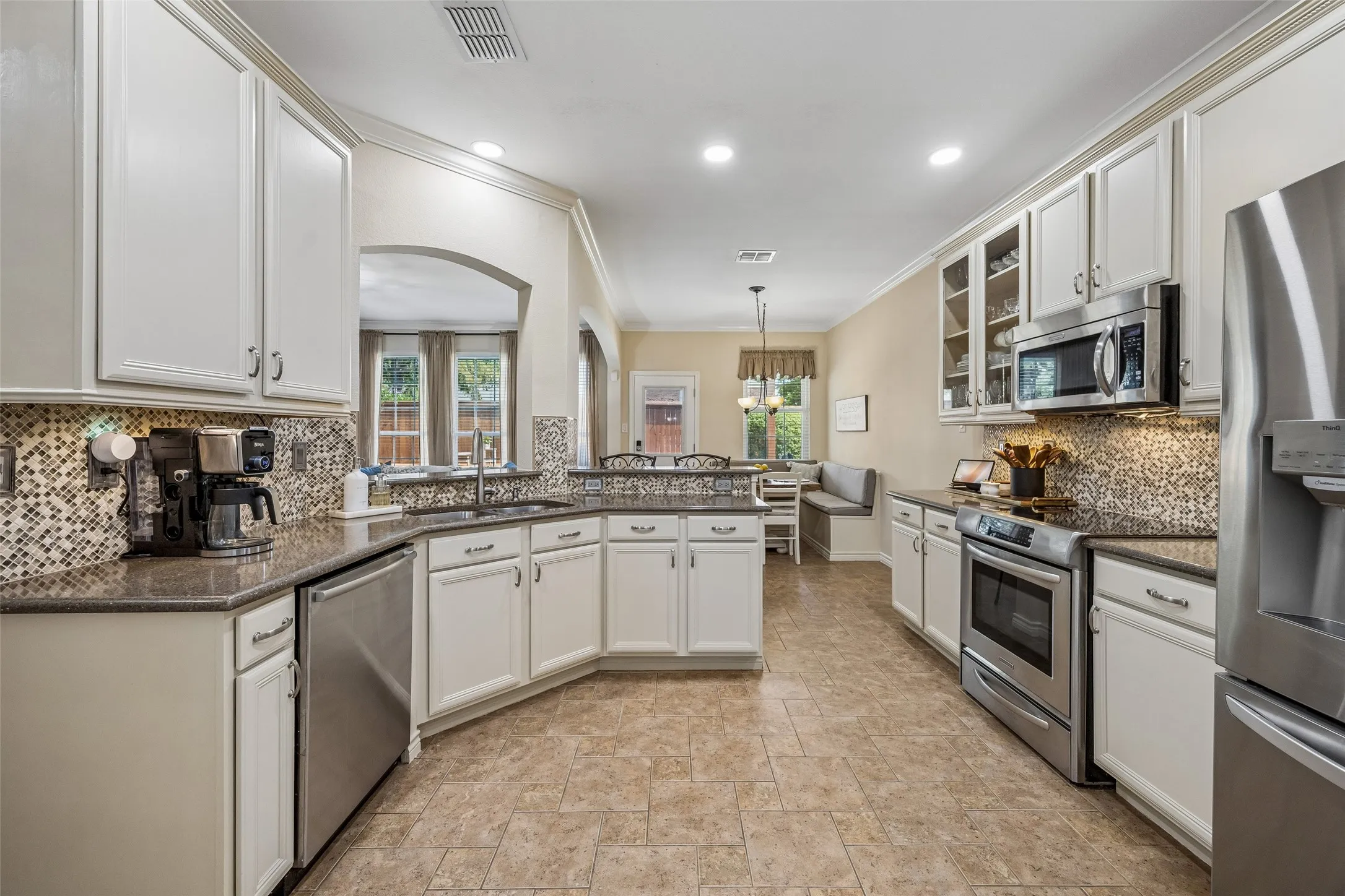 Plenty of Prep and Storage Space - The kitchen offers expansive counter space, abundant cabinetry, glass-front display cabinets, stainless appliances, and an undermount sink, giving the room both function and visual interest.