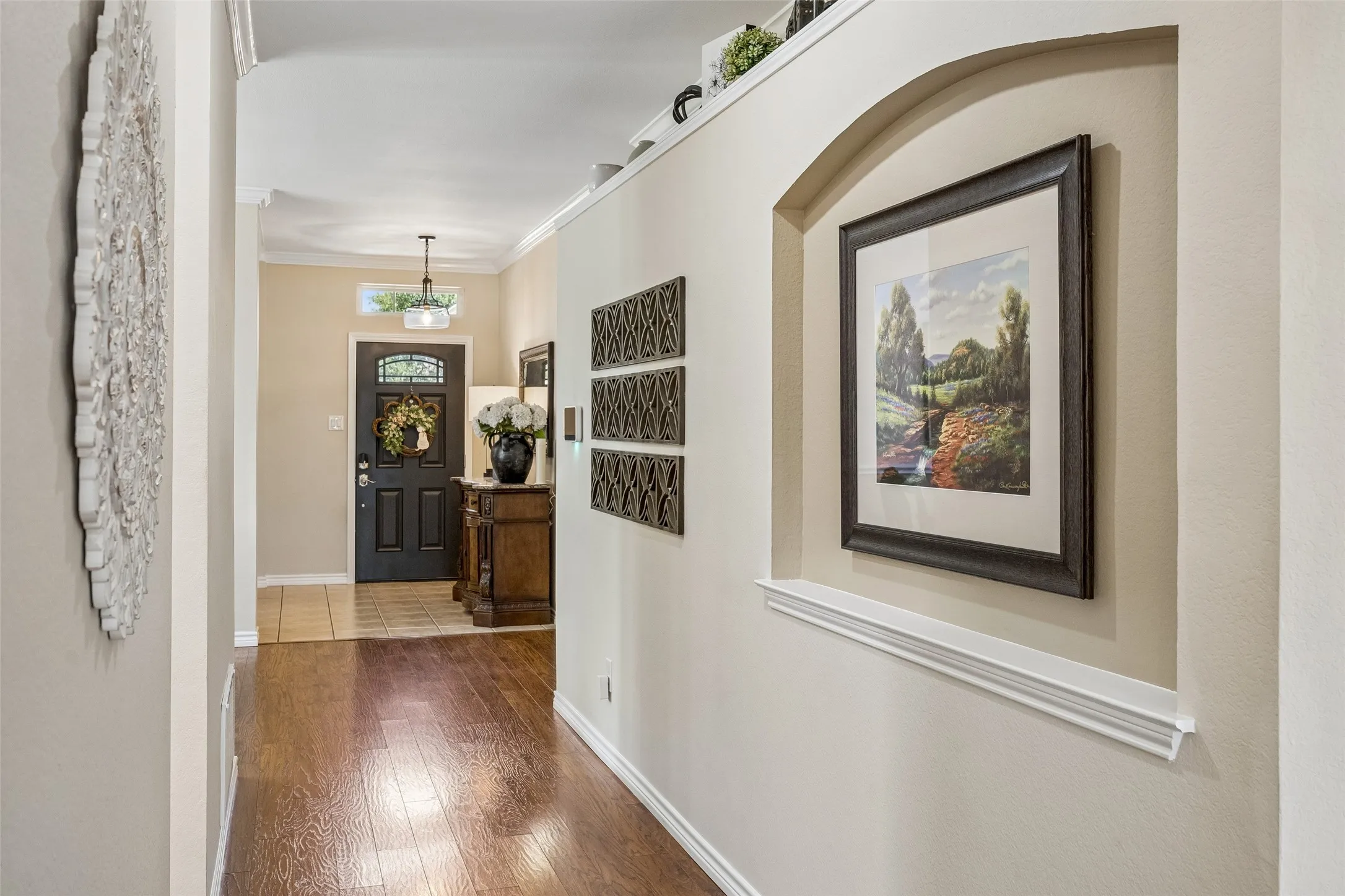 Architectural Detail Along the Entry Hall - As you move towards the secondary bedrooms, take not of the updated flooring, crown molding, and a recessed art niche, adding visual interest while connecting the entry to the home’s main living areas.