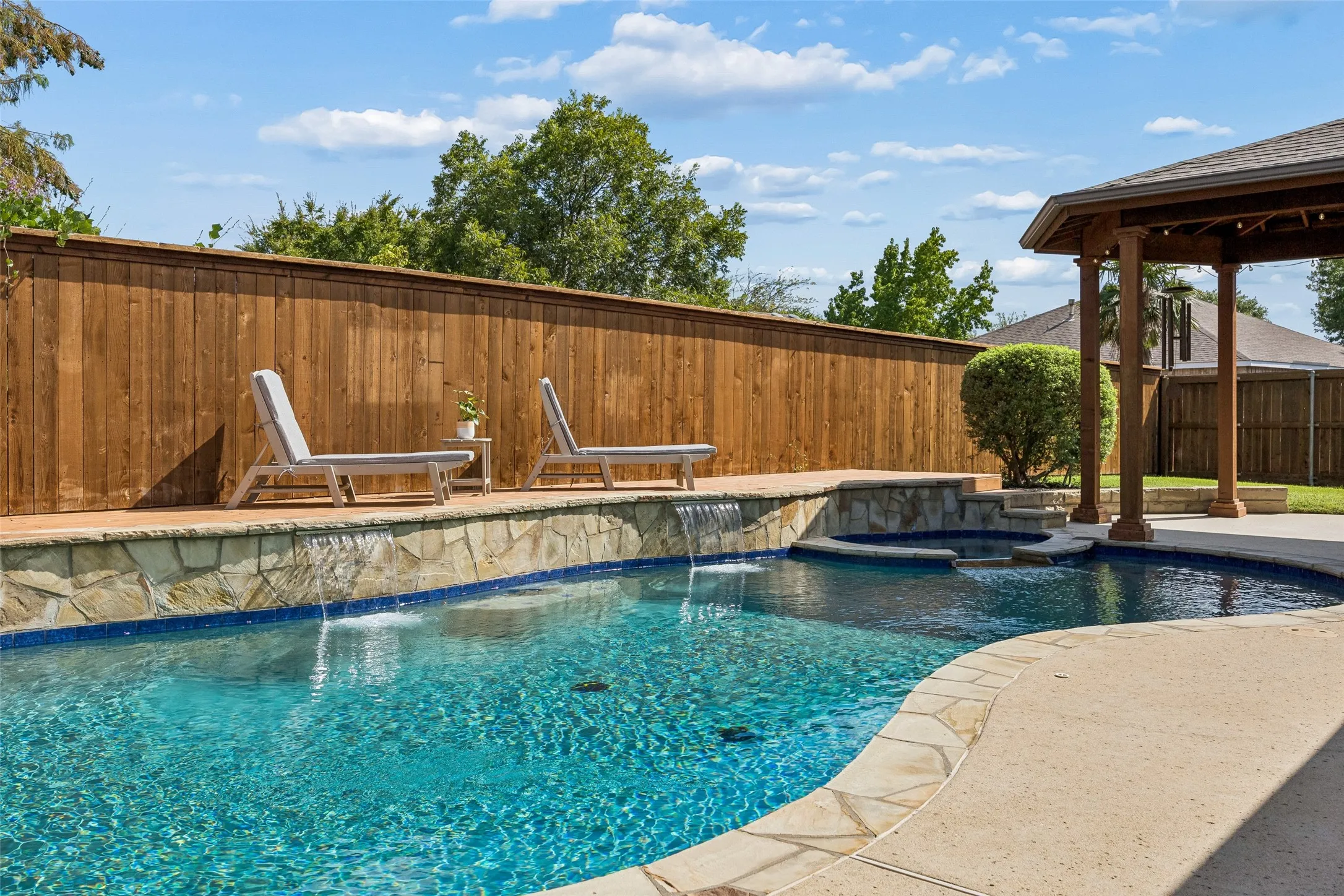 A Backyard Made for Relaxing - Cascading waterfalls, an attached spa, stone coping, and an upgraded pool finish create an inviting setting for cooling off, unwinding, or spending an afternoon outdoors.