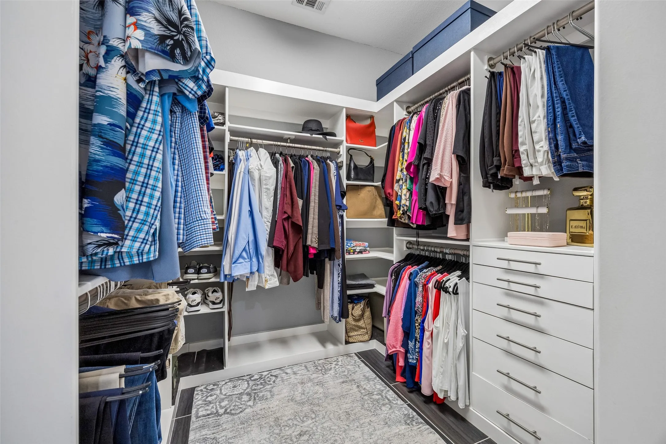 A Custom Closet That Maximizes Every Inch - The primary walk-in closet is outfitted with built-in drawers, shelving, shoe storage, overhead storage, and separate hanging areas for a highly organized use of space.