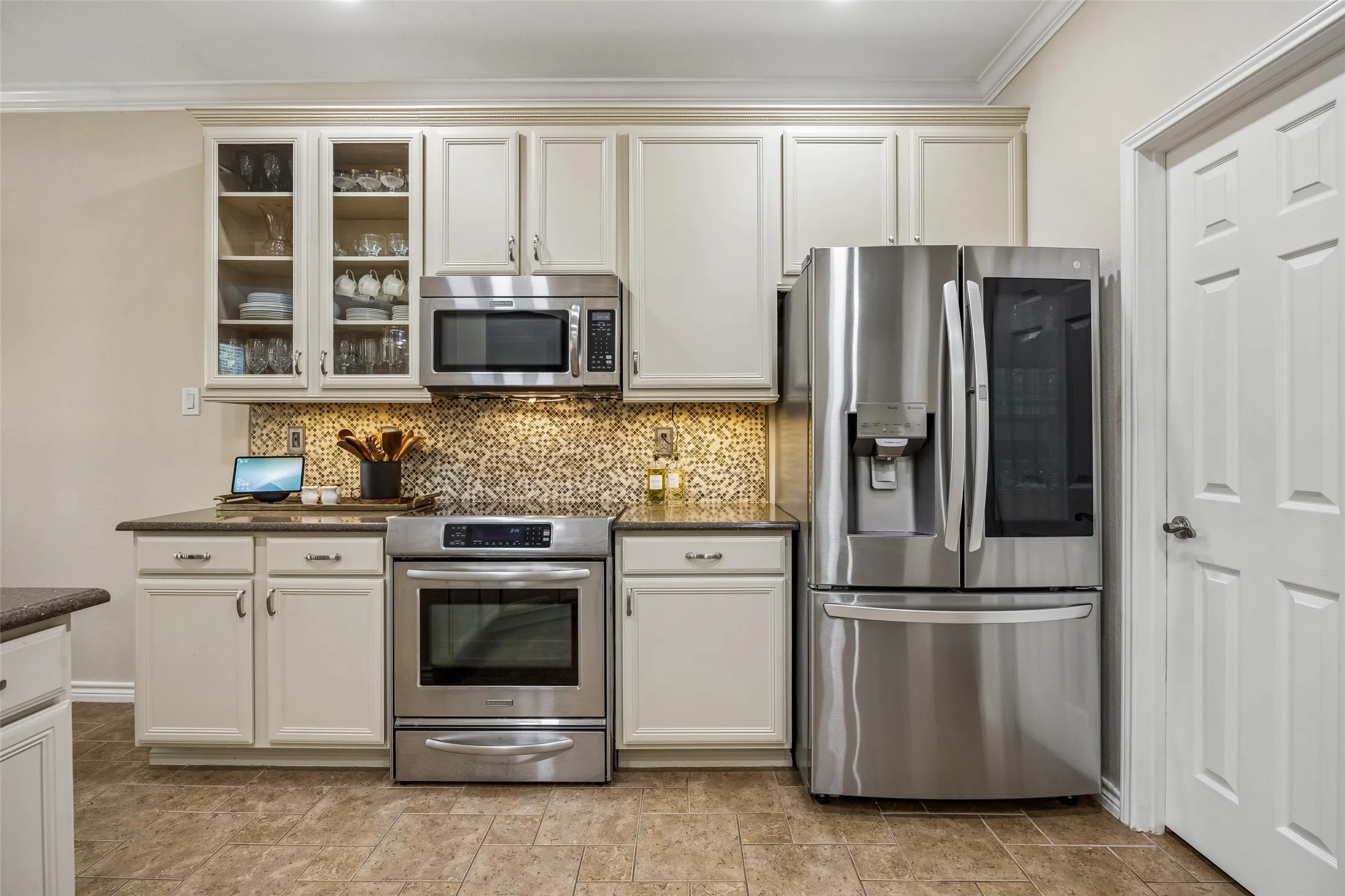 Storage with Style - Glass-front cabinets, crown molding, updated hardware, and a generous run of cabinetry provide practical storage while adding character to the kitchen.