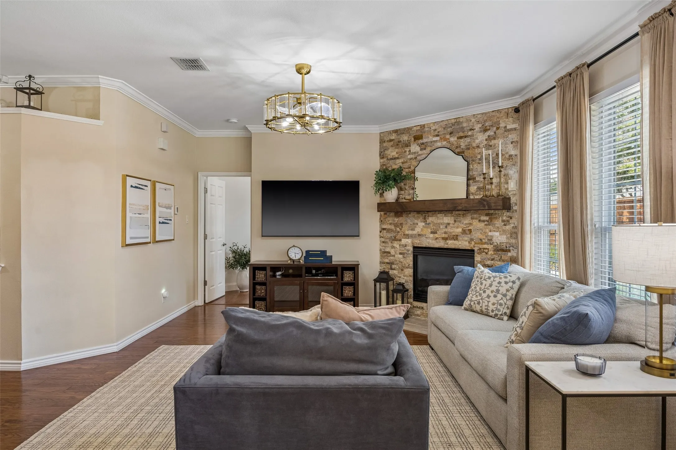 Family Room with Space to Settle In - The family room offers generous wall space, updated flooring, crown molding, and a gas fireplace framed in stacked stone, creating a comfortable central gathering space with plenty of flexibility for everyday living.