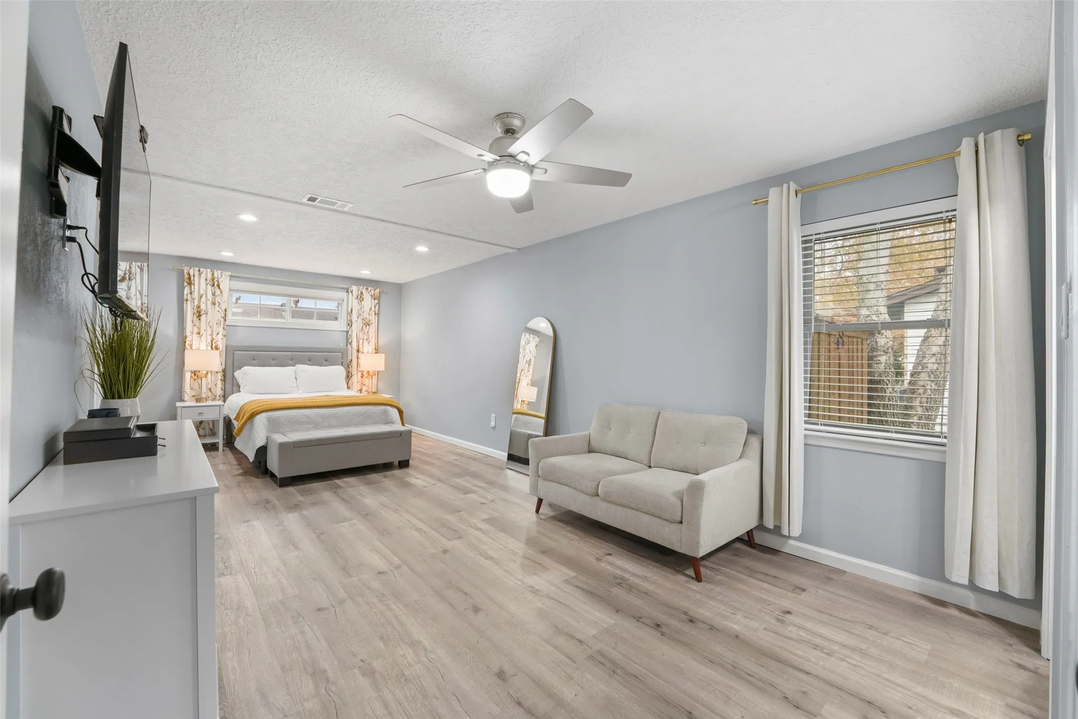 Spacious room featuring wood-finish flooring, recessed lighting, and a ceiling fan