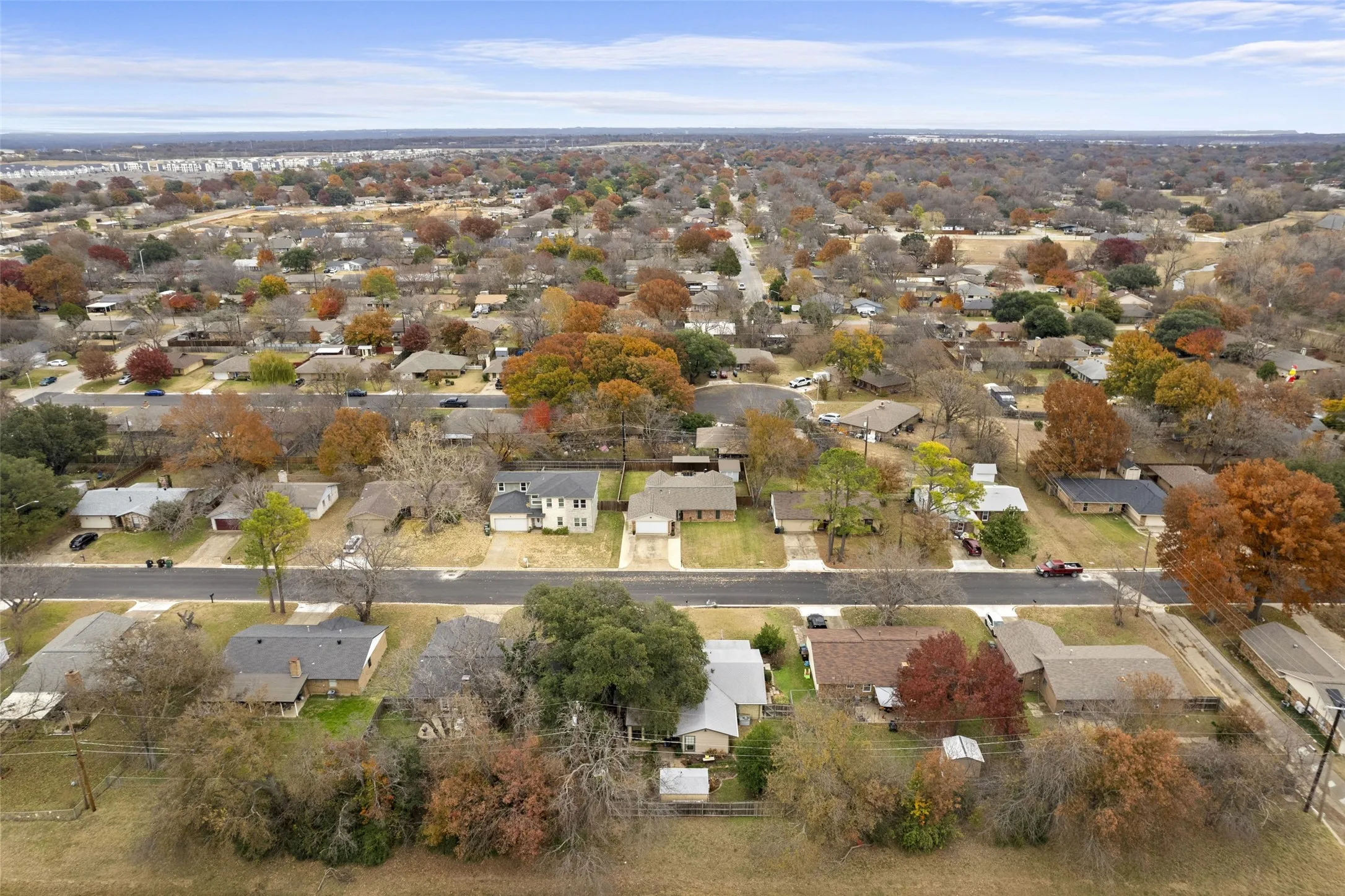 Residential neighborhood featuring a grid street pattern, mature trees with seasonal foliage, and single-story homes with varied rooflines