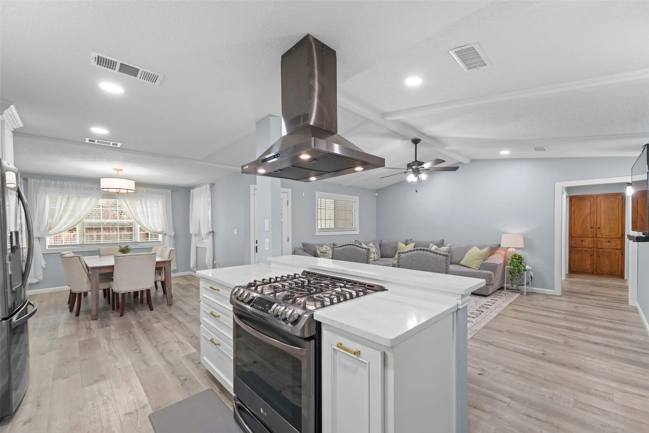 Kitchen island featuring a gas range, white countertop, and gold-toned hardware