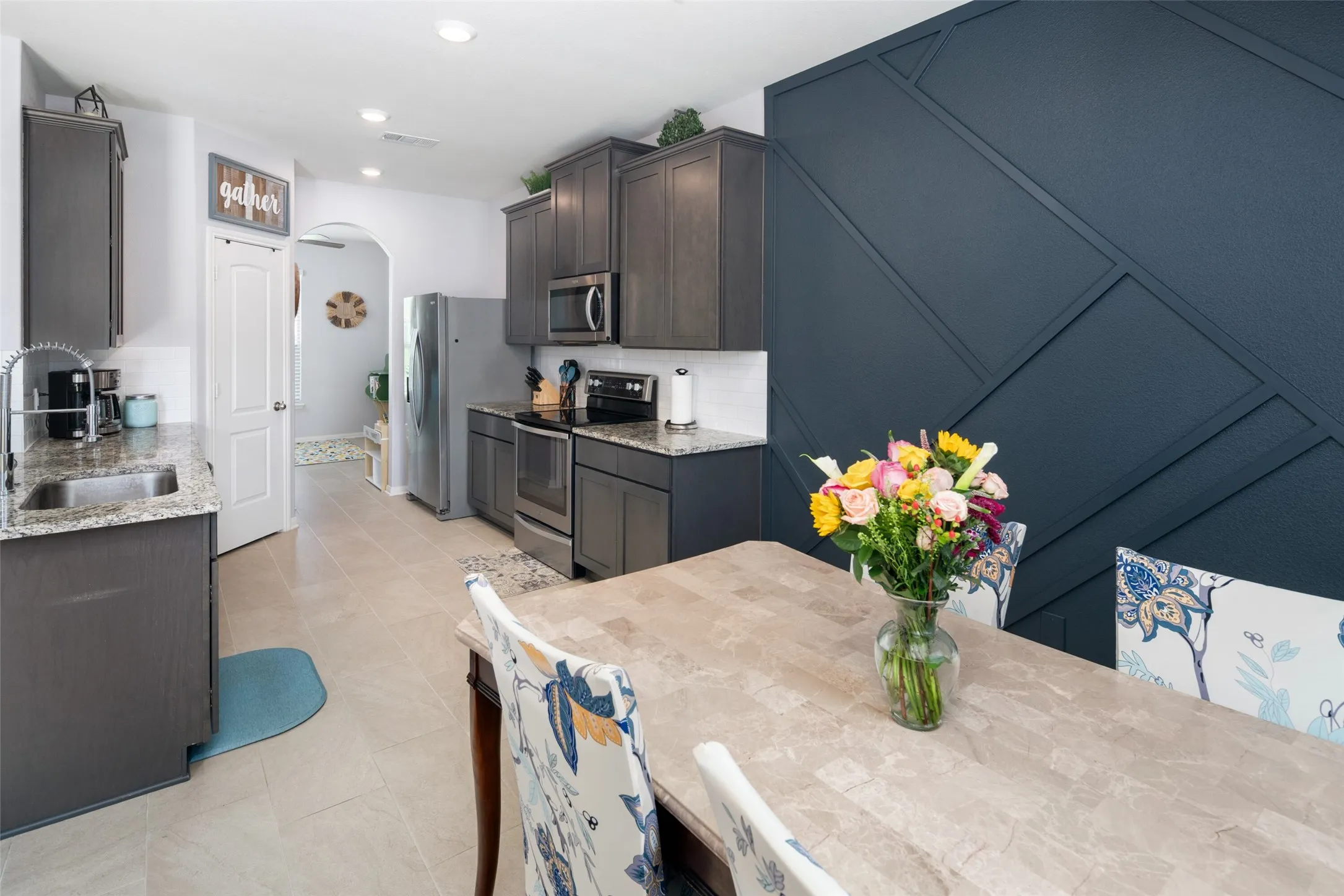 Modern kitchen featuring dark wood-finish cabinetry, stainless steel appliances, and light-toned wood-finish flooring