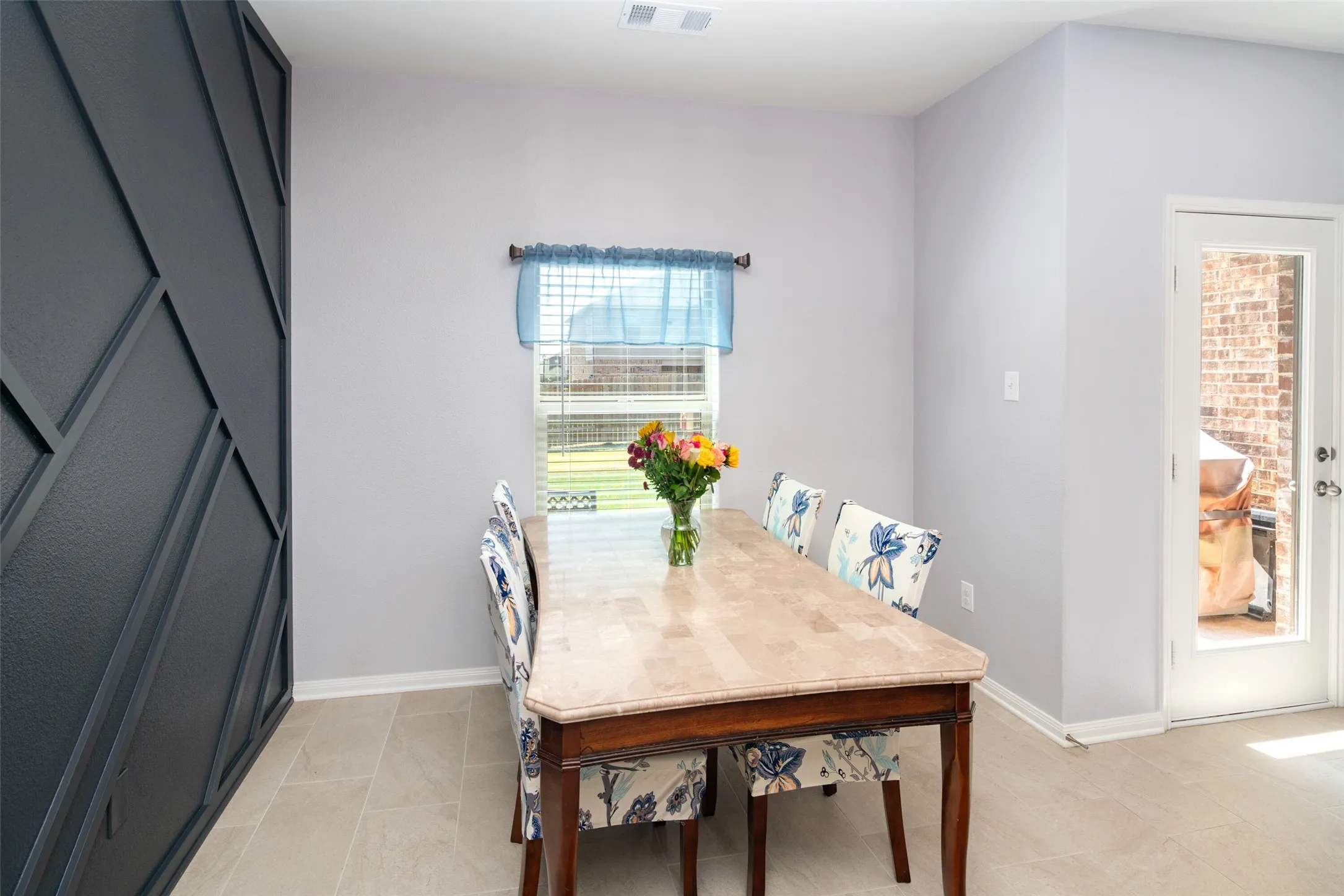 Feature wall with geometric paneling, light gray painted walls, tile flooring, and a glass-paneled exterior door