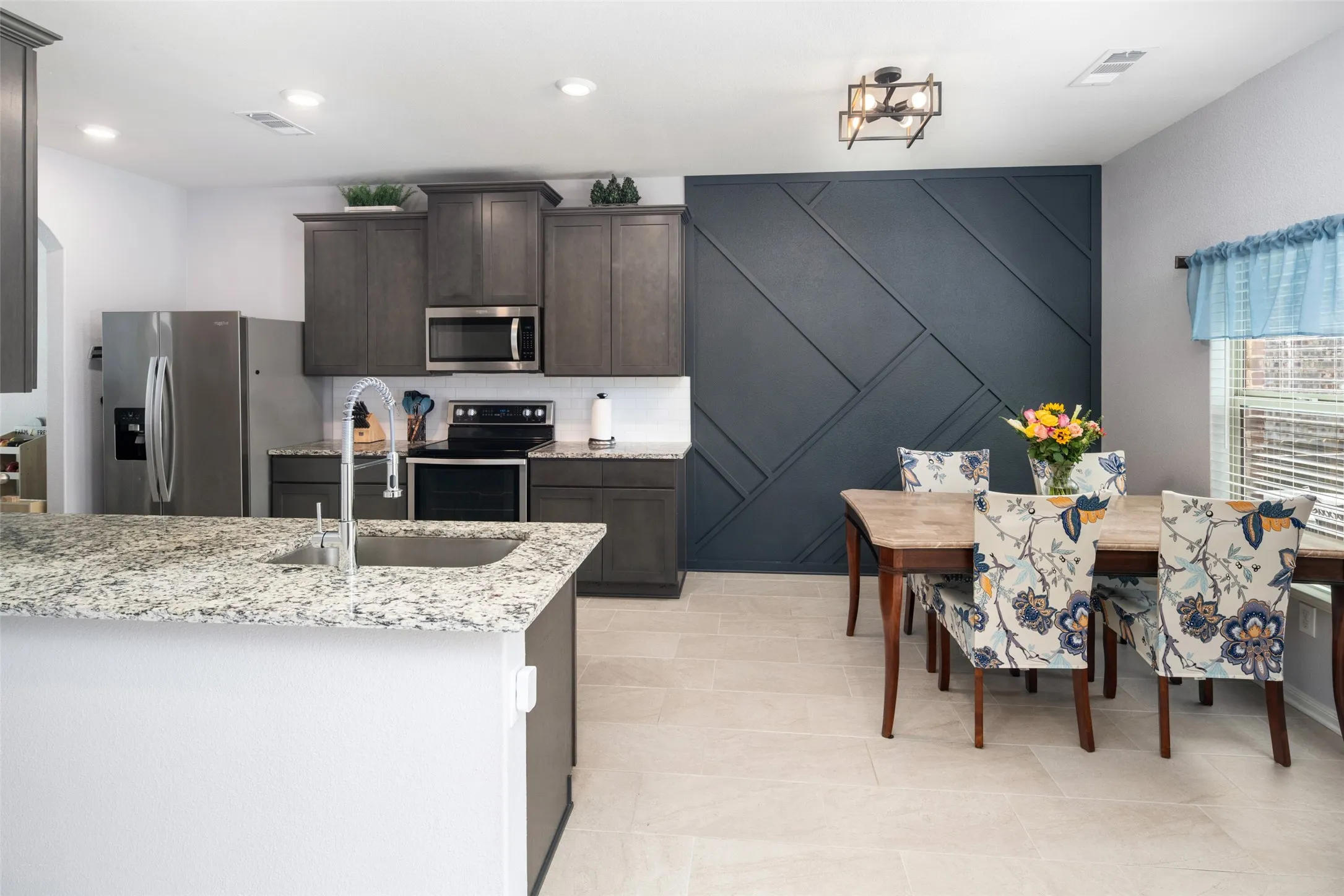 Kitchen featuring an island with an undermount sink, stainless steel appliances, recessed lighting, and light-toned tile flooring