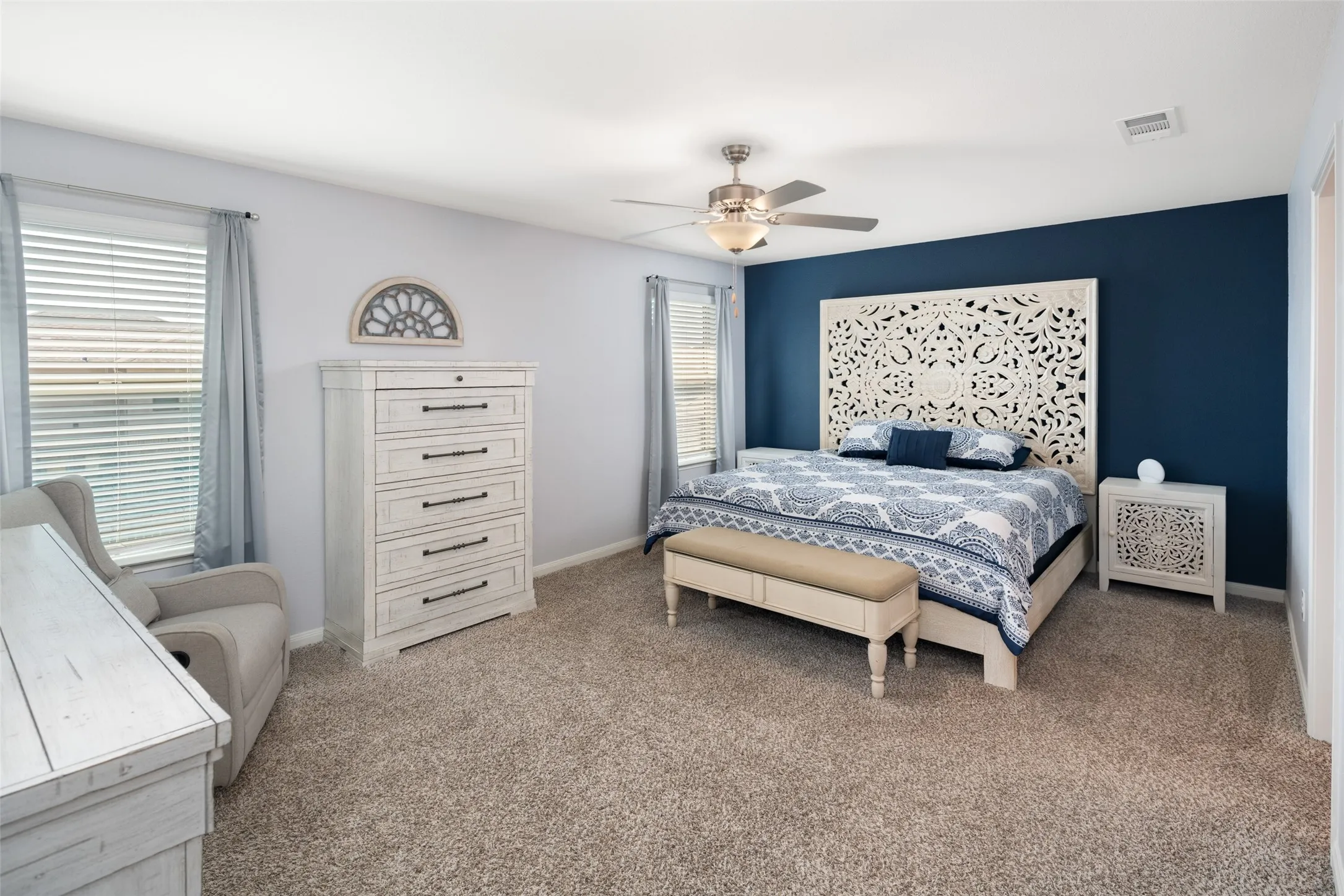 Plush carpeting, a ceiling fan with integrated lighting, and multiple windows with blinds