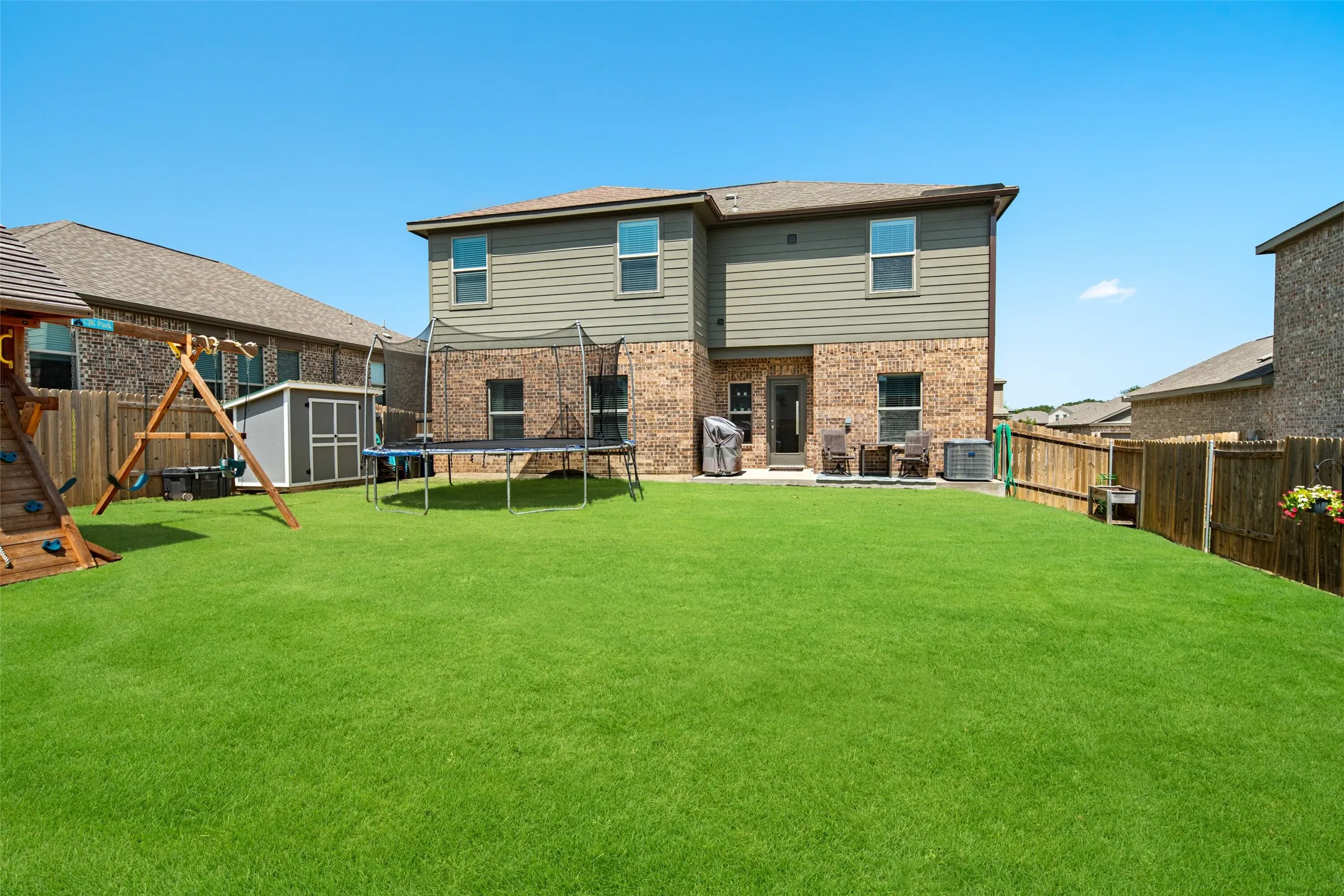 Expansive backyard with a manicured lawn, wood privacy fencing, and a concrete patio