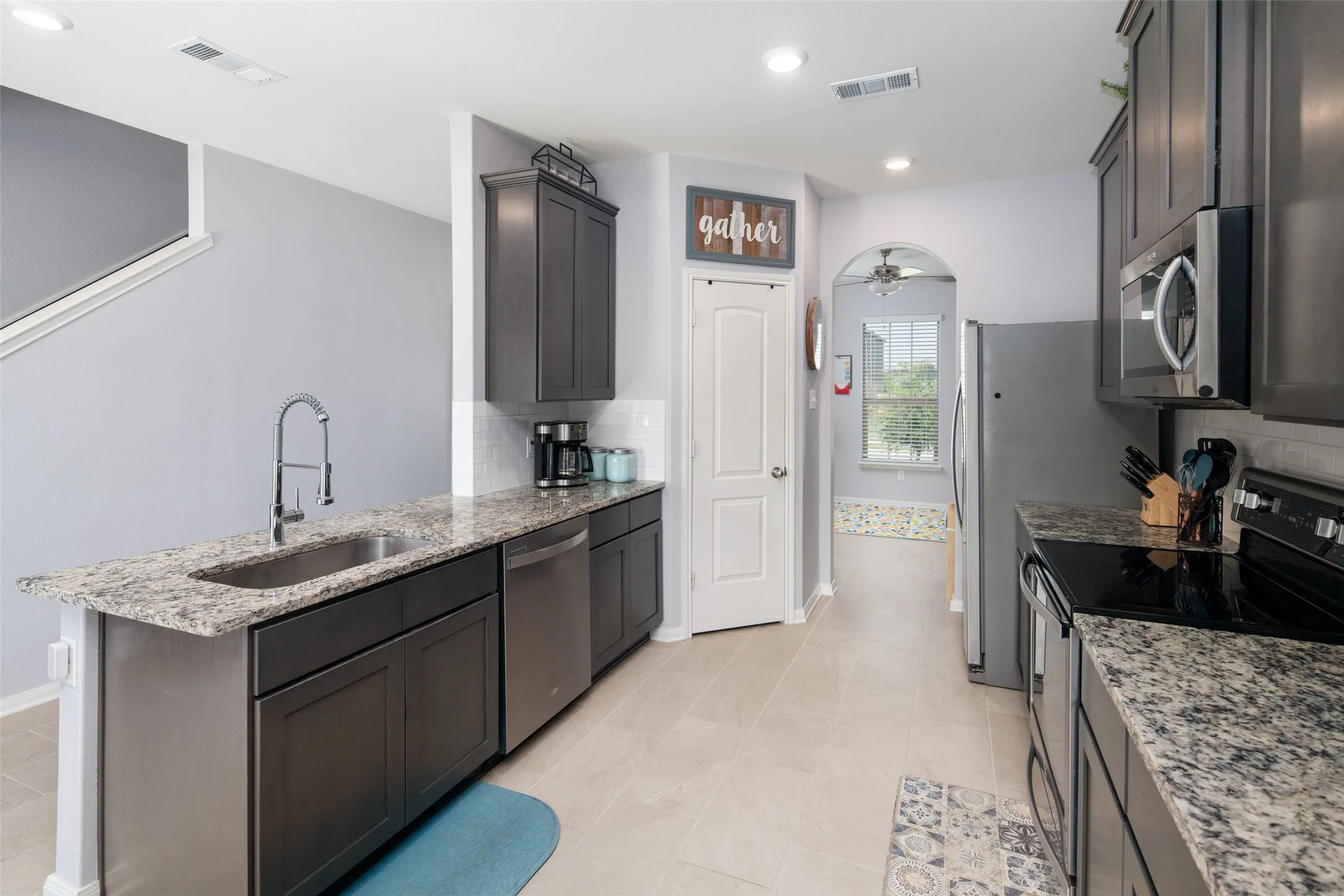 Chef's kitchen featuring dark cabinetry, granite-style countertops, stainless steel appliances, and a large island with prep sink