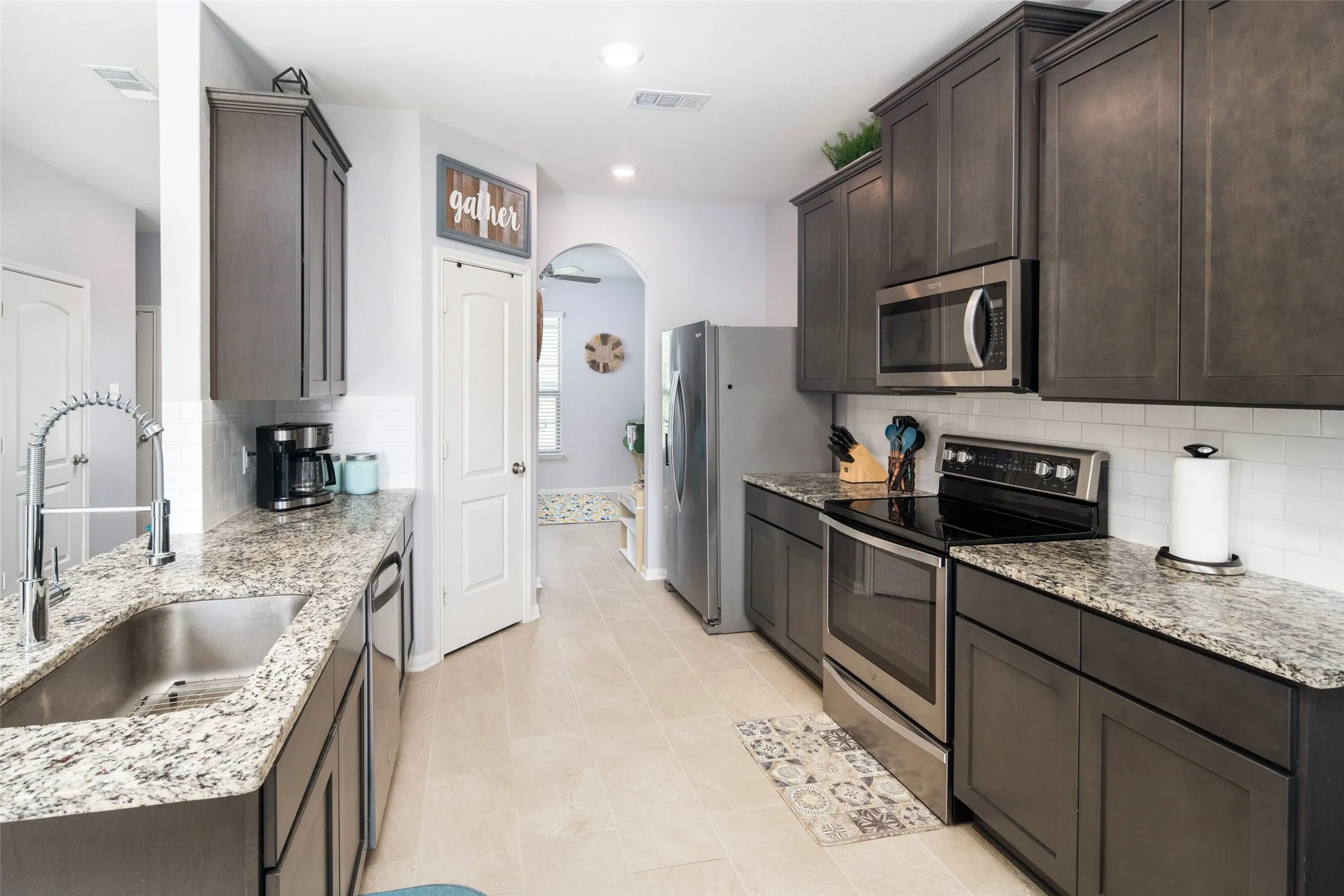 Kitchen with dark wood-finish cabinetry, light-toned countertops, and stainless steel appliances