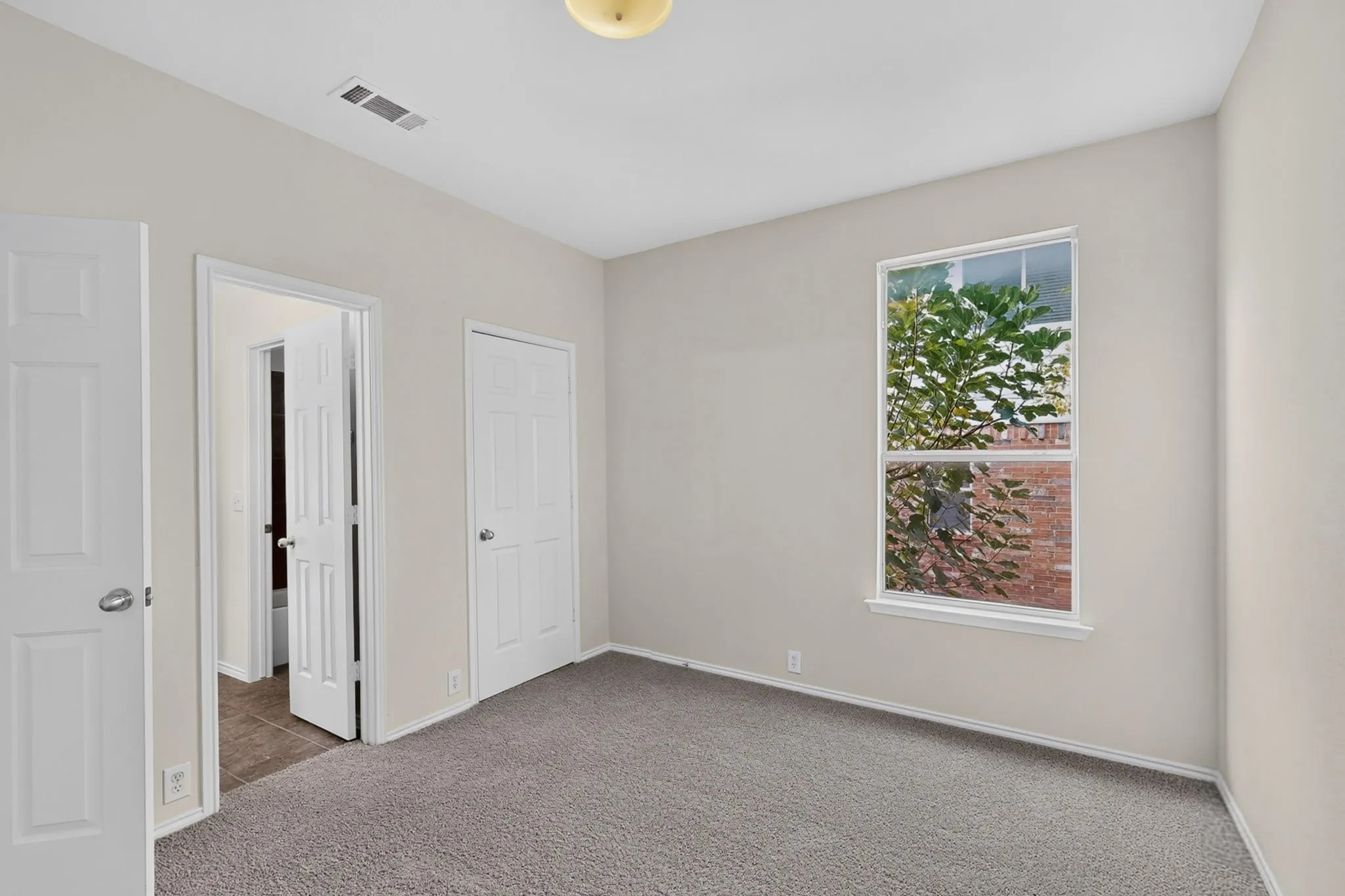Window with white trim, light-toned walls, and grey carpet flooring