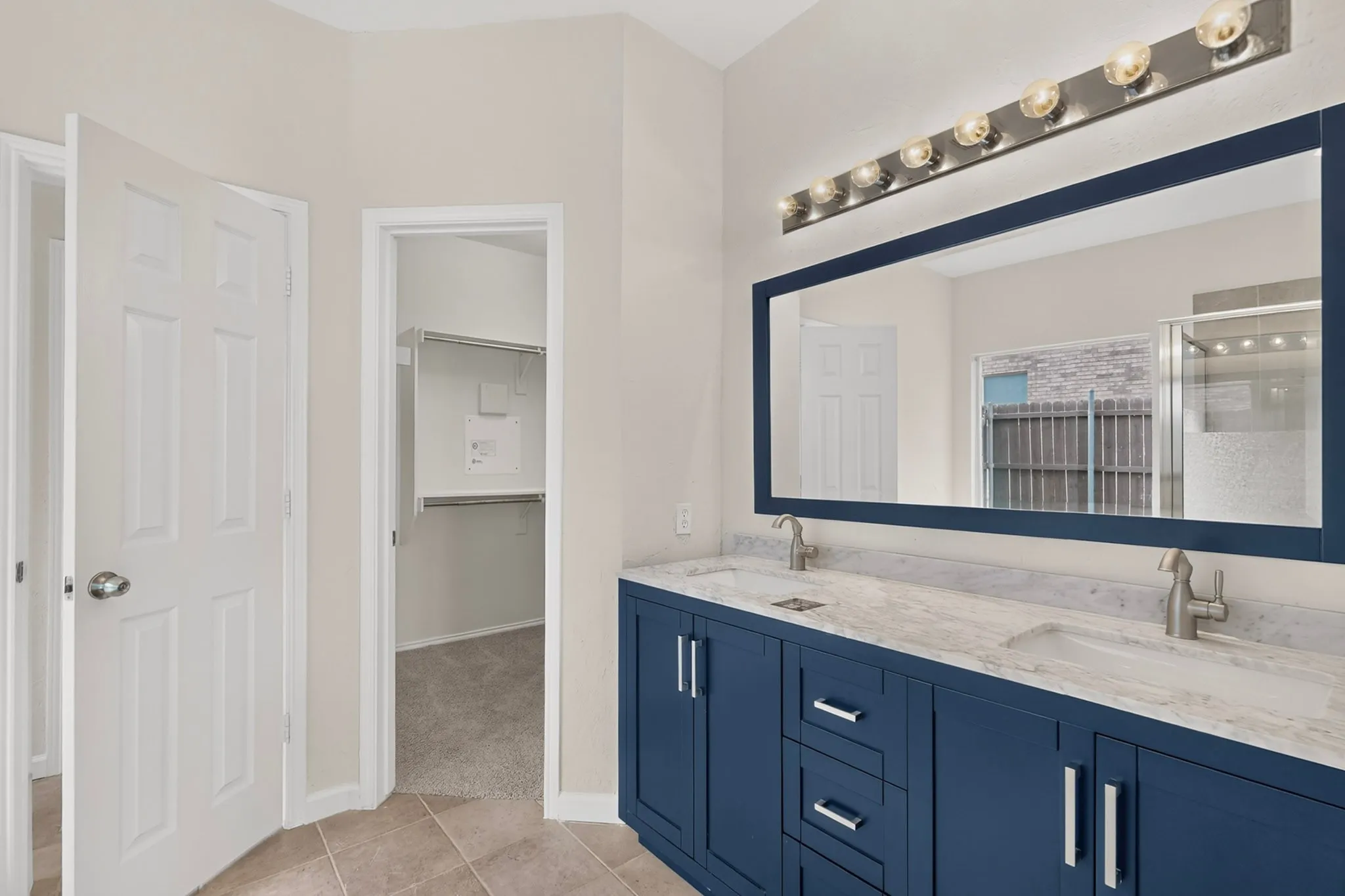 Dual basin vanity with blue cabinetry, brushed nickel hardware, and a stone-finish countertop