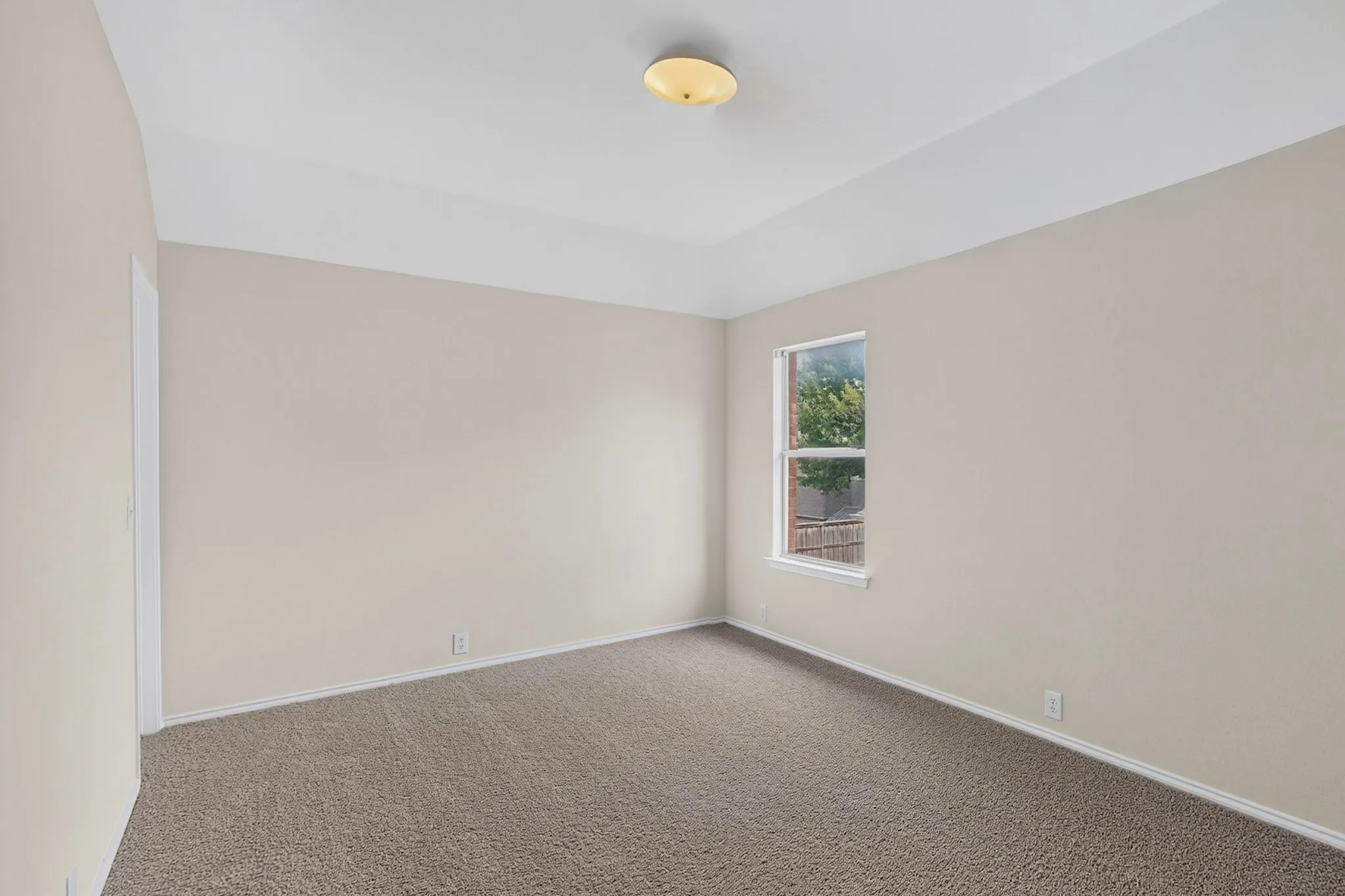 Recessed ceiling detail, neutral wall paint, carpet flooring, window with white trim, and a flush mount ceiling light