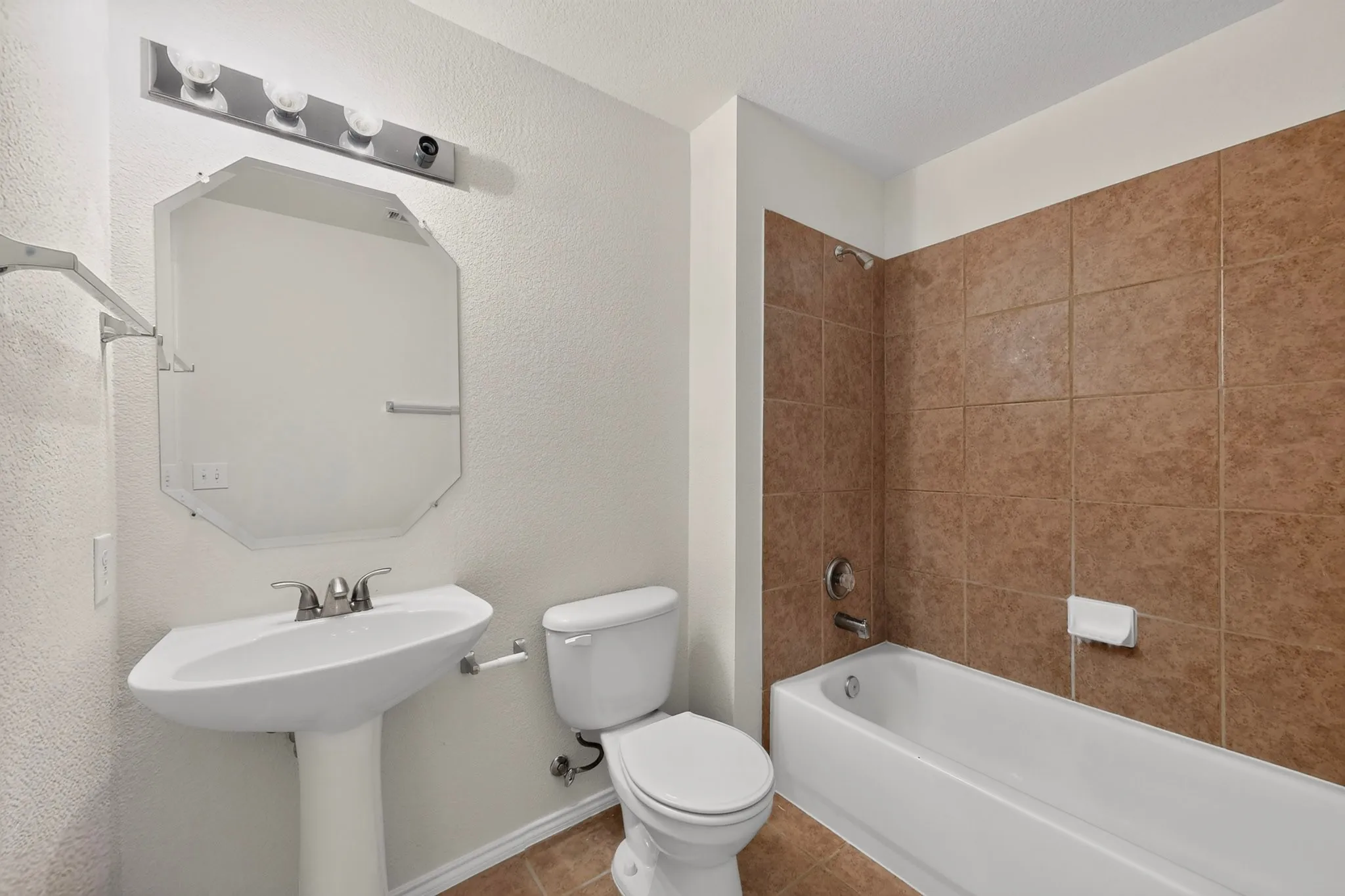 Pedestal sink with chrome faucet, octagonal mirror, and four-bulb vanity light