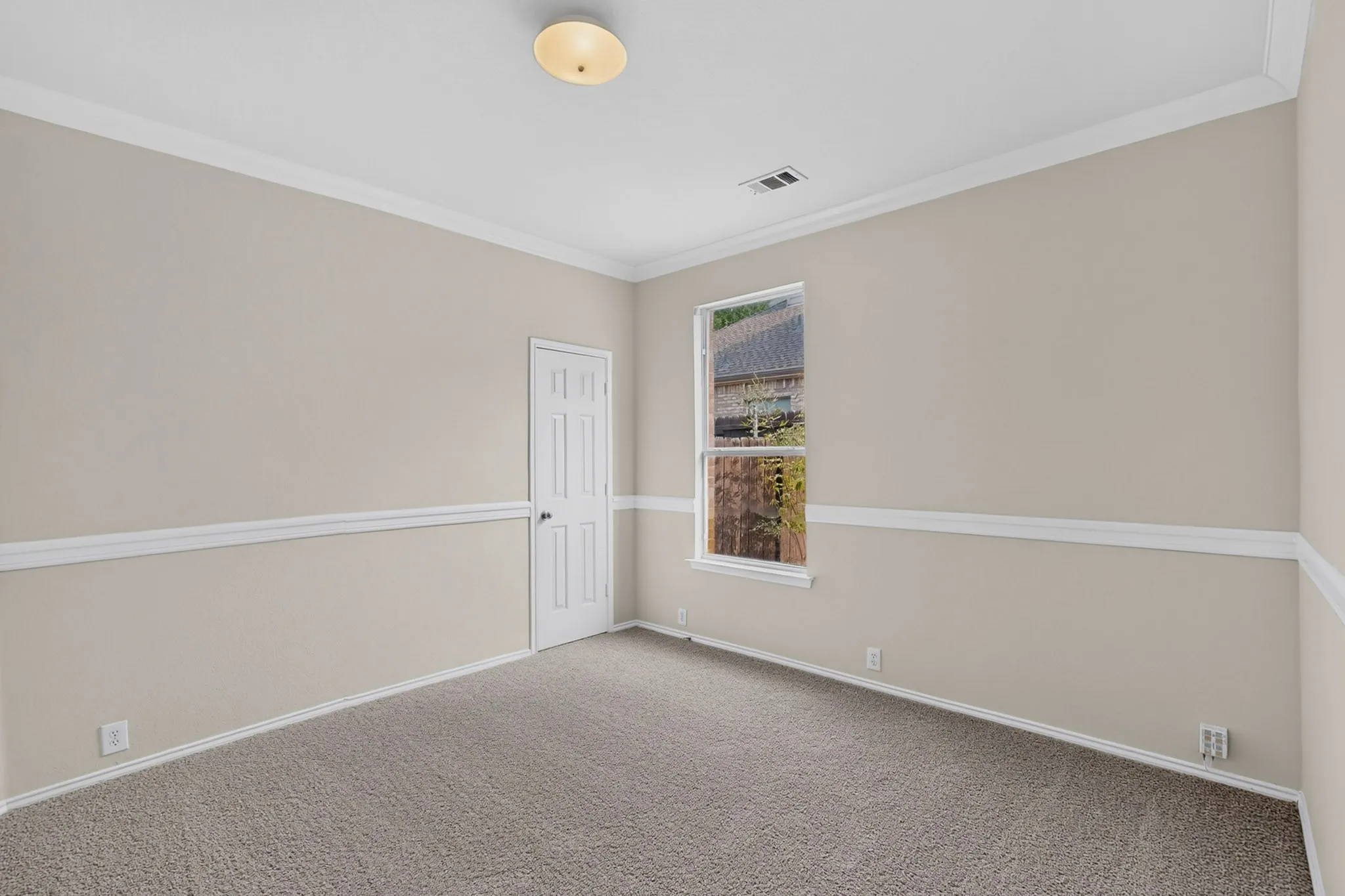 Neutral tone walls with crown molding and chair rail detailing, carpeted flooring, and a single window