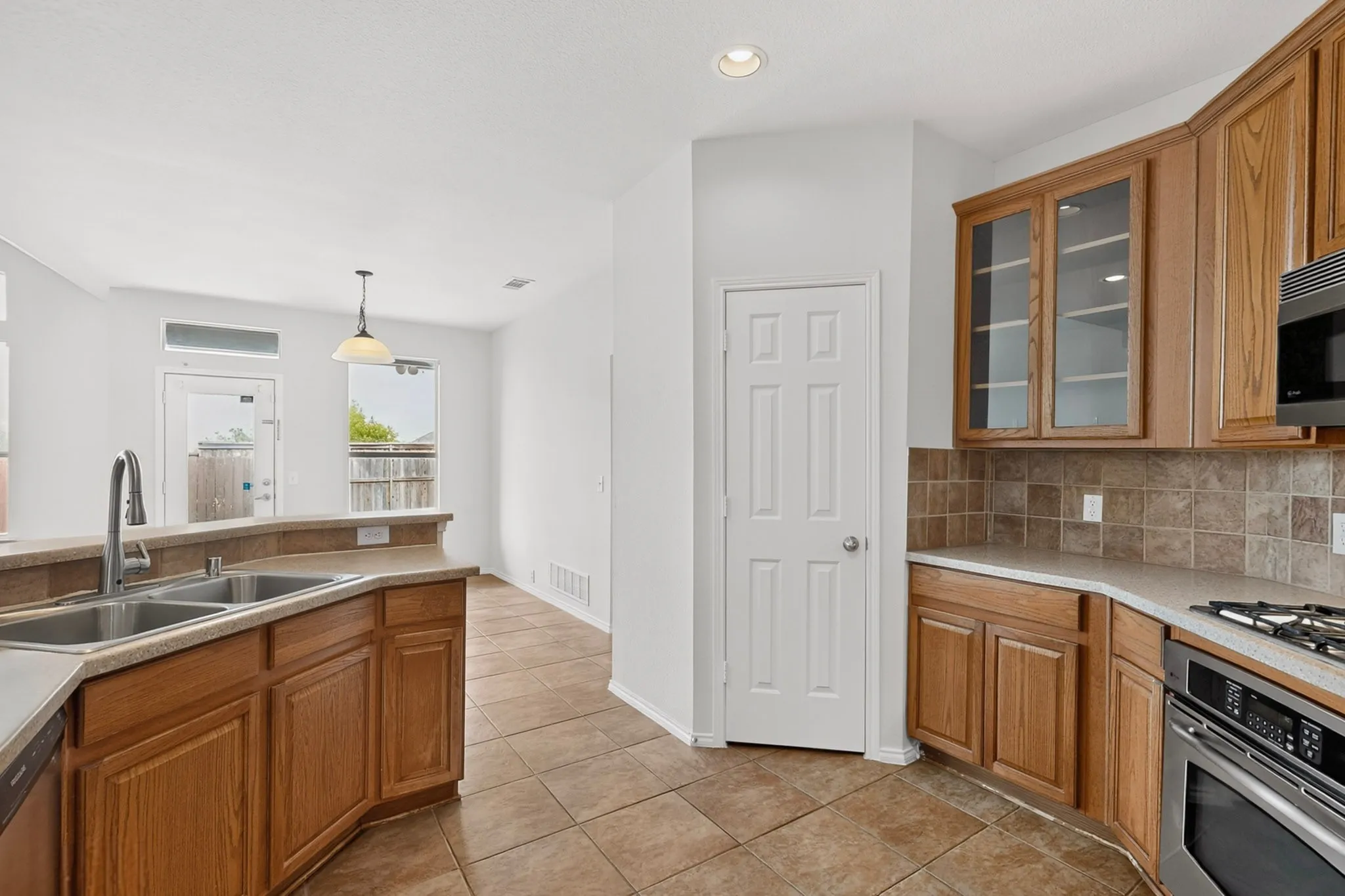 Kitchen featuring wood cabinetry, stainless steel sink with gooseneck faucet, integrated stainless steel appliances, and a tiled backsplash