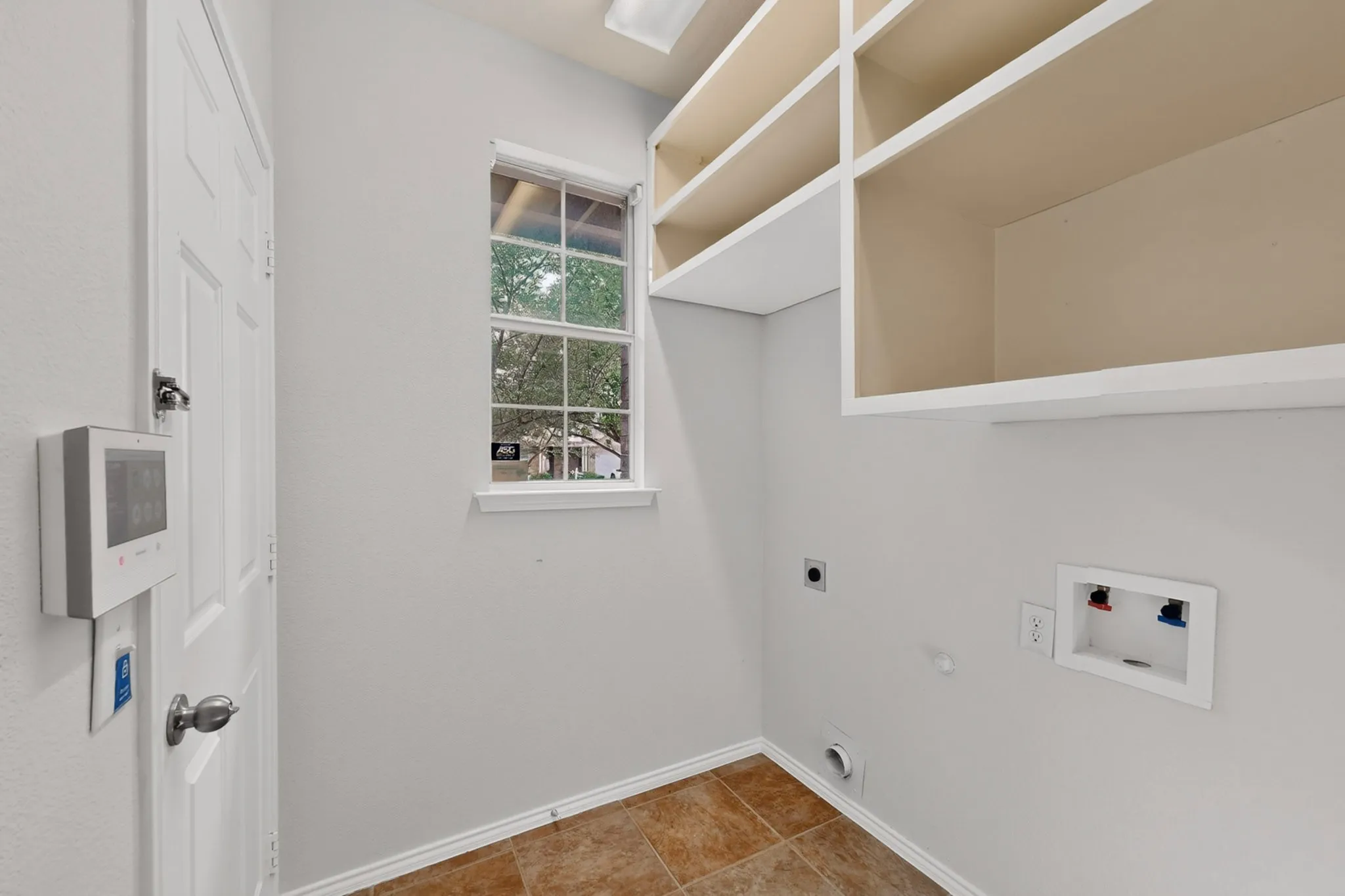 Laundry space with tiled flooring and upper built-in shelving
