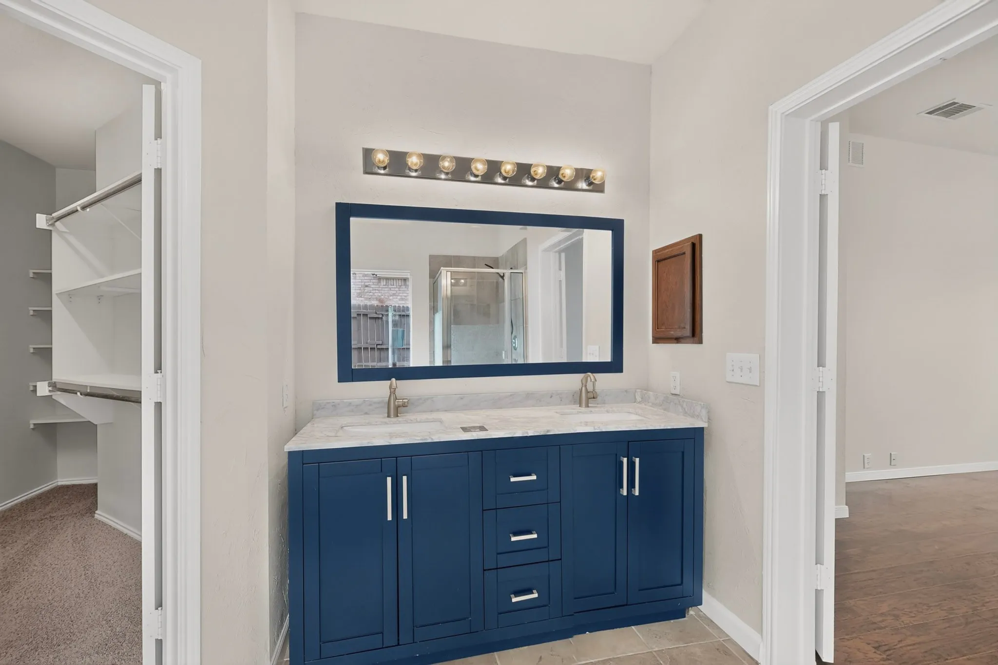 Bathroom vanity with dual sinks, a blue cabinet base, and a rectangular mirror