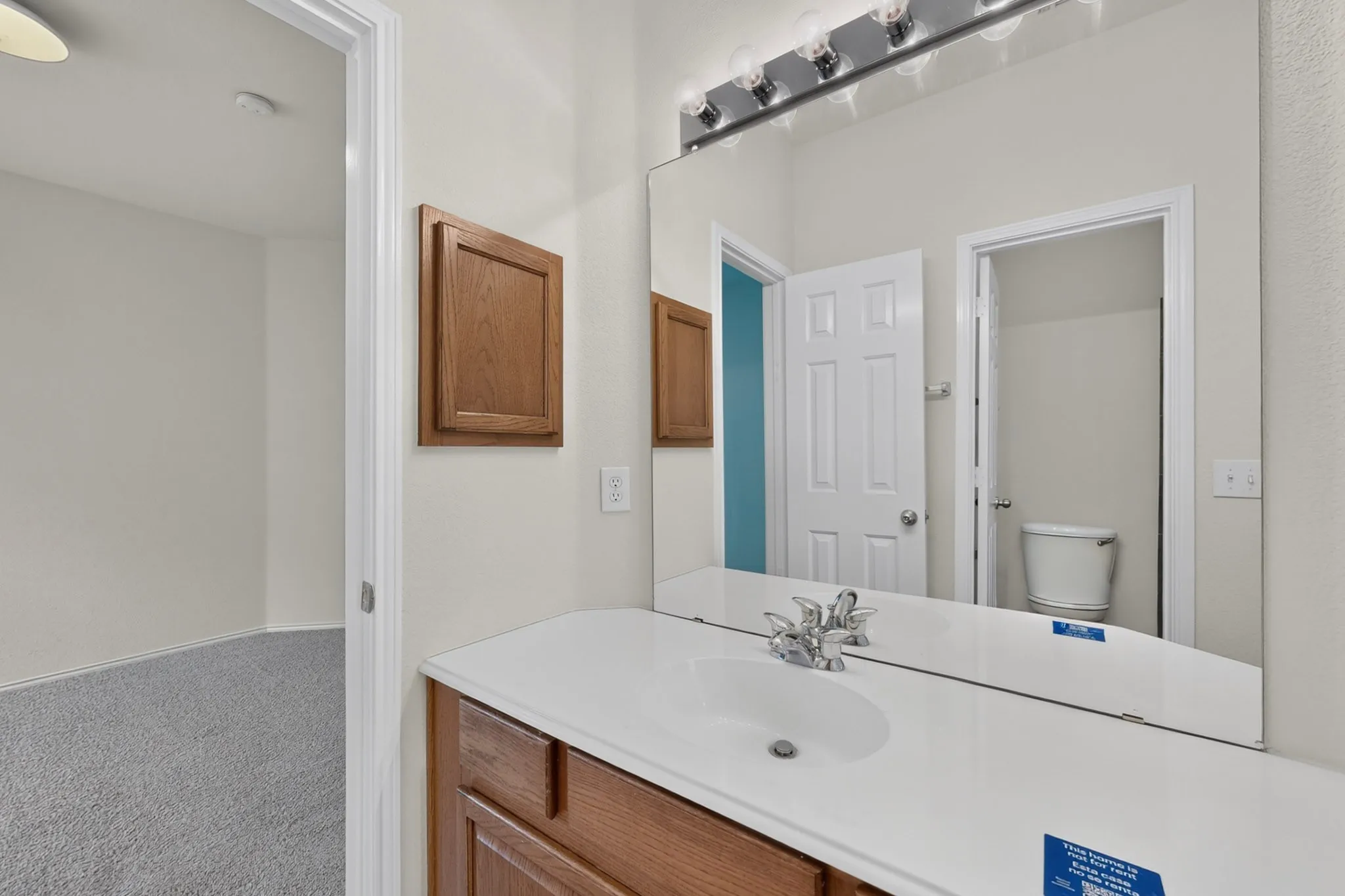 Vanity with integrated sink, wood-finish cabinetry, and overhead lighting