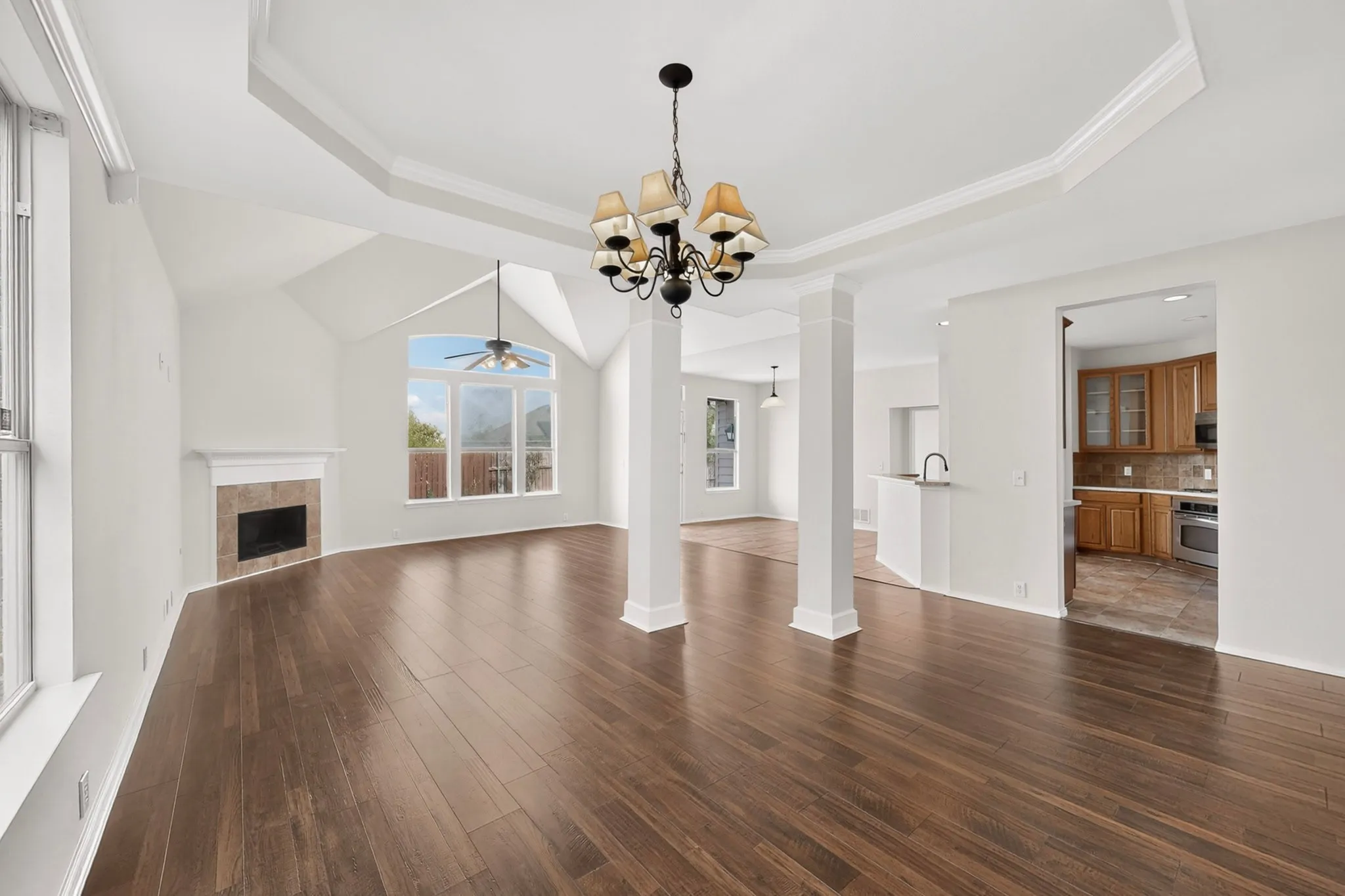 Spacious living area featuring wood-finish flooring, a fireplace with a tile surround, and vaulted ceilings