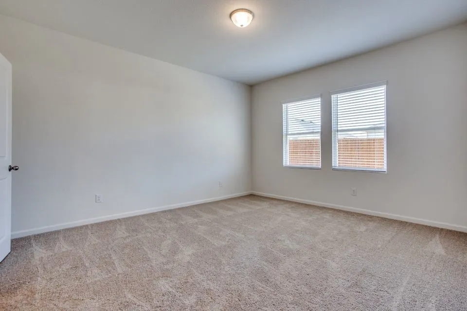 Neutral-toned wall-to-wall carpeting, white painted walls, and two windows with horizontal blinds