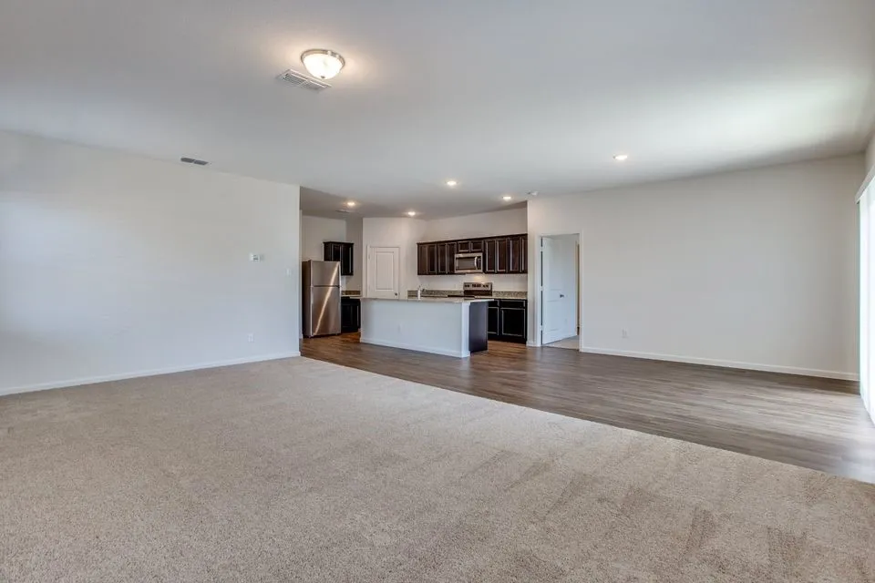 Open-concept living space featuring a kitchen with dark wood-finish cabinetry, stainless steel appliances, and a central island
