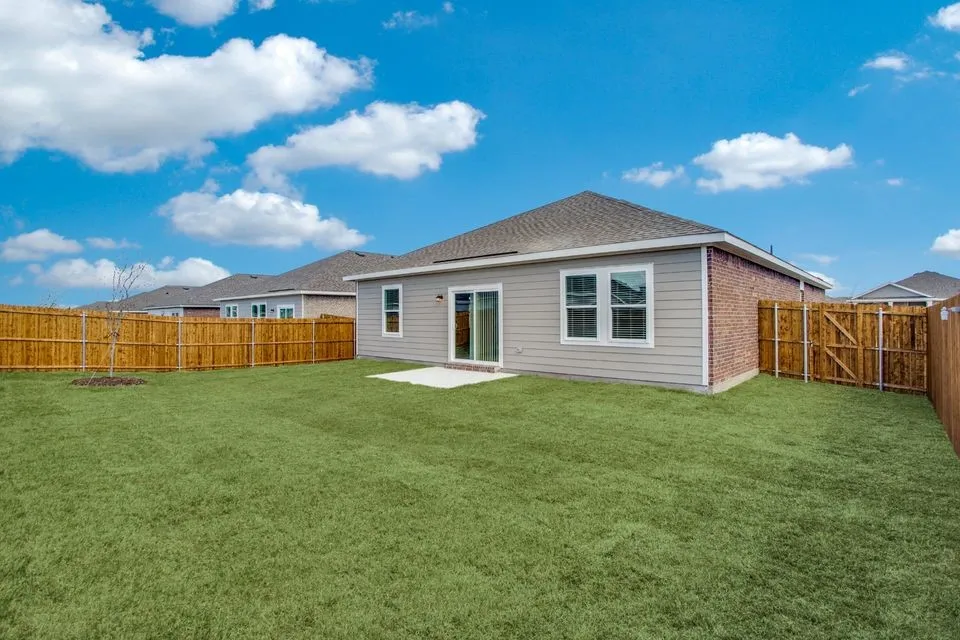 Expansive backyard featuring a manicured lawn, wood fencing, and a concrete patio