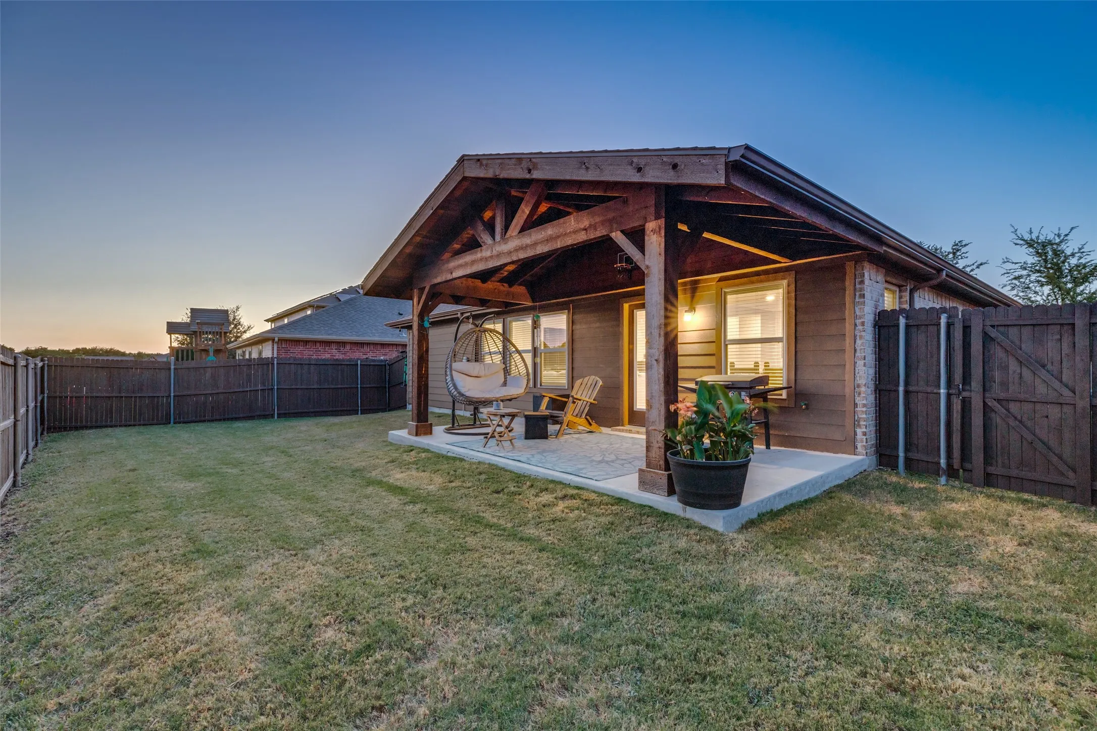 Expansive backyard featuring a covered patio with a vaulted wood-beam ceiling, concrete flooring, and a wood privacy fence