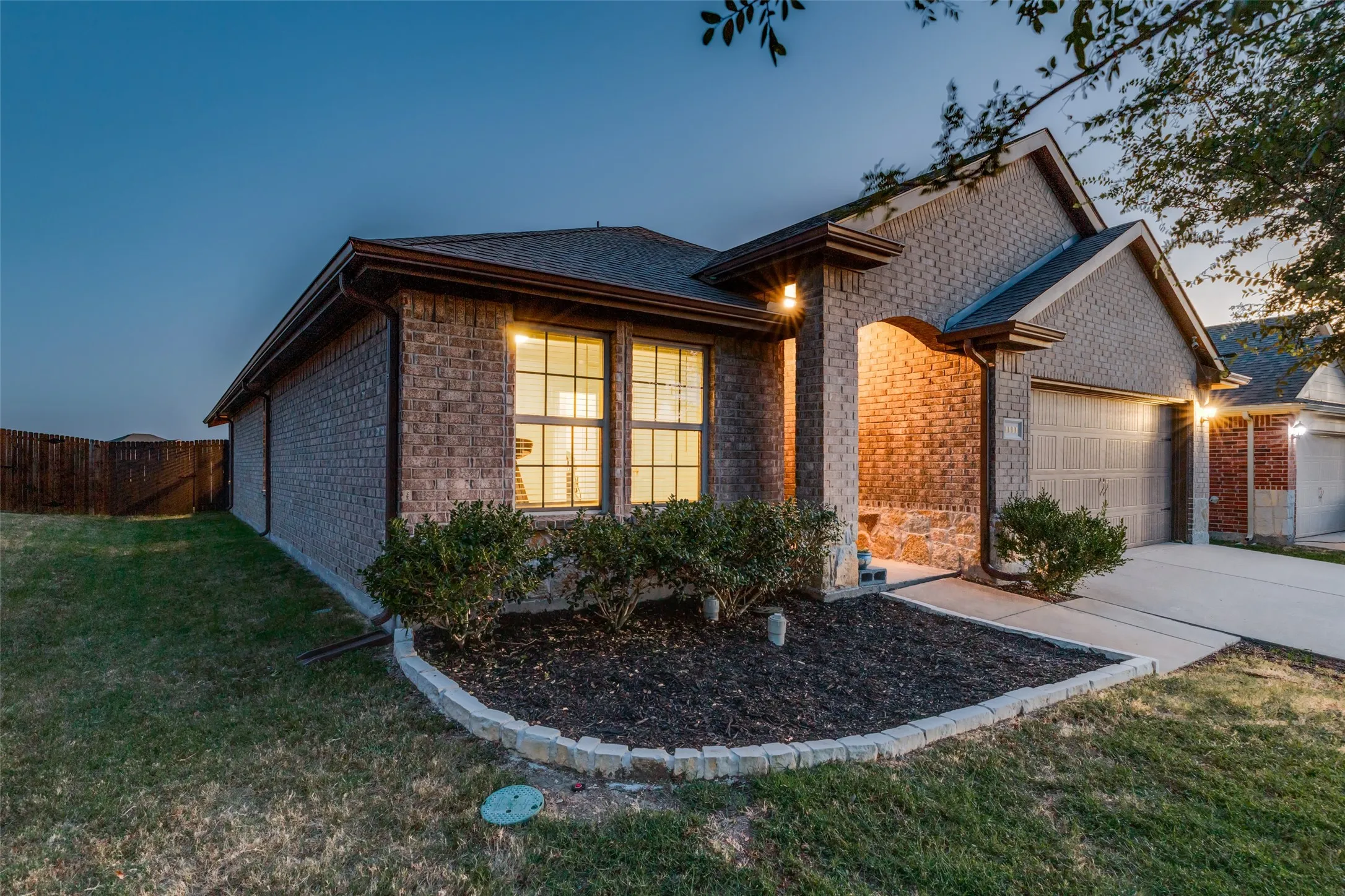 Brick exterior with a stone accent facade, attached two-car garage, covered entry, and landscaped front yard