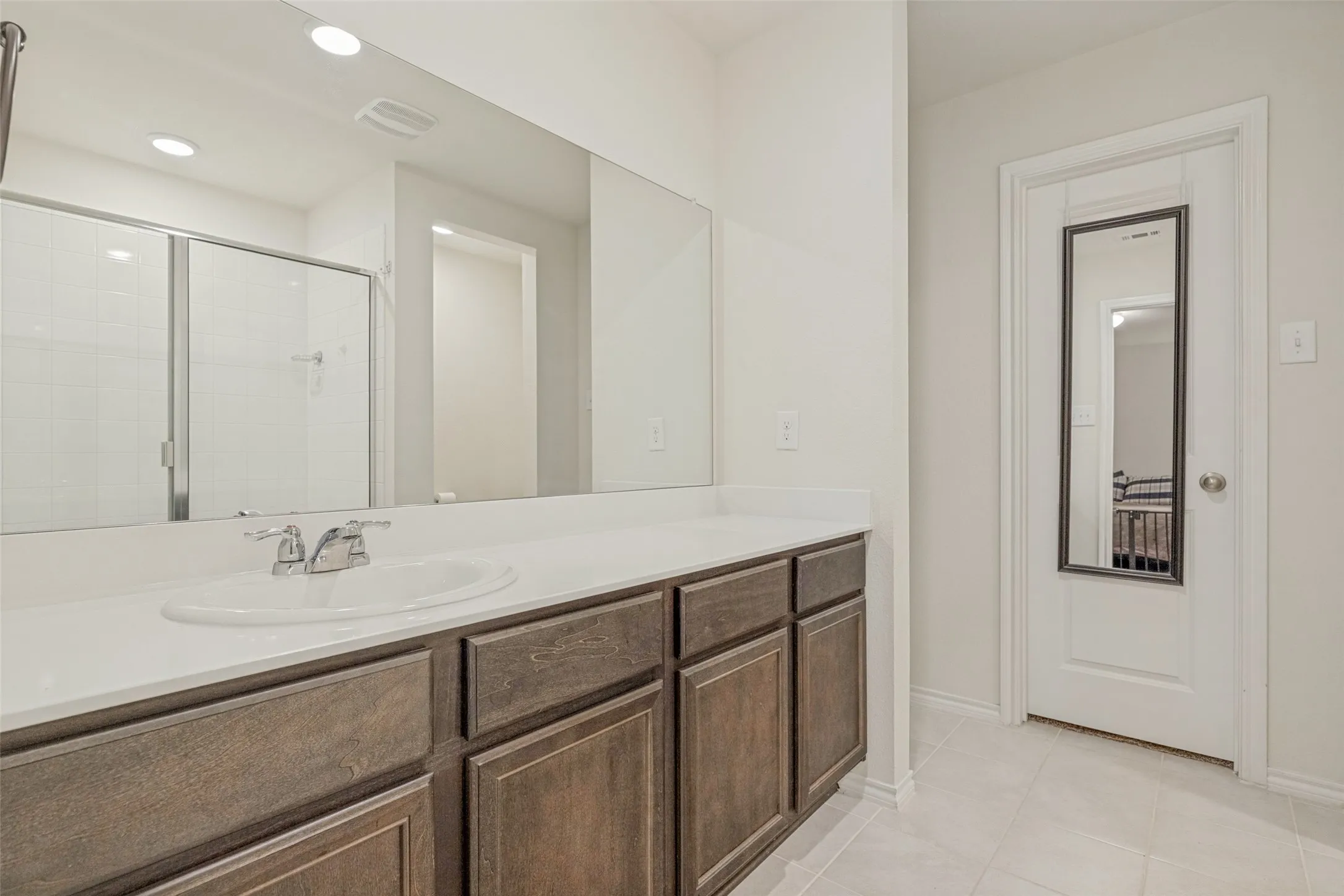 Extended vanity with a light-colored countertop, integrated sink, and wood-finish cabinetry