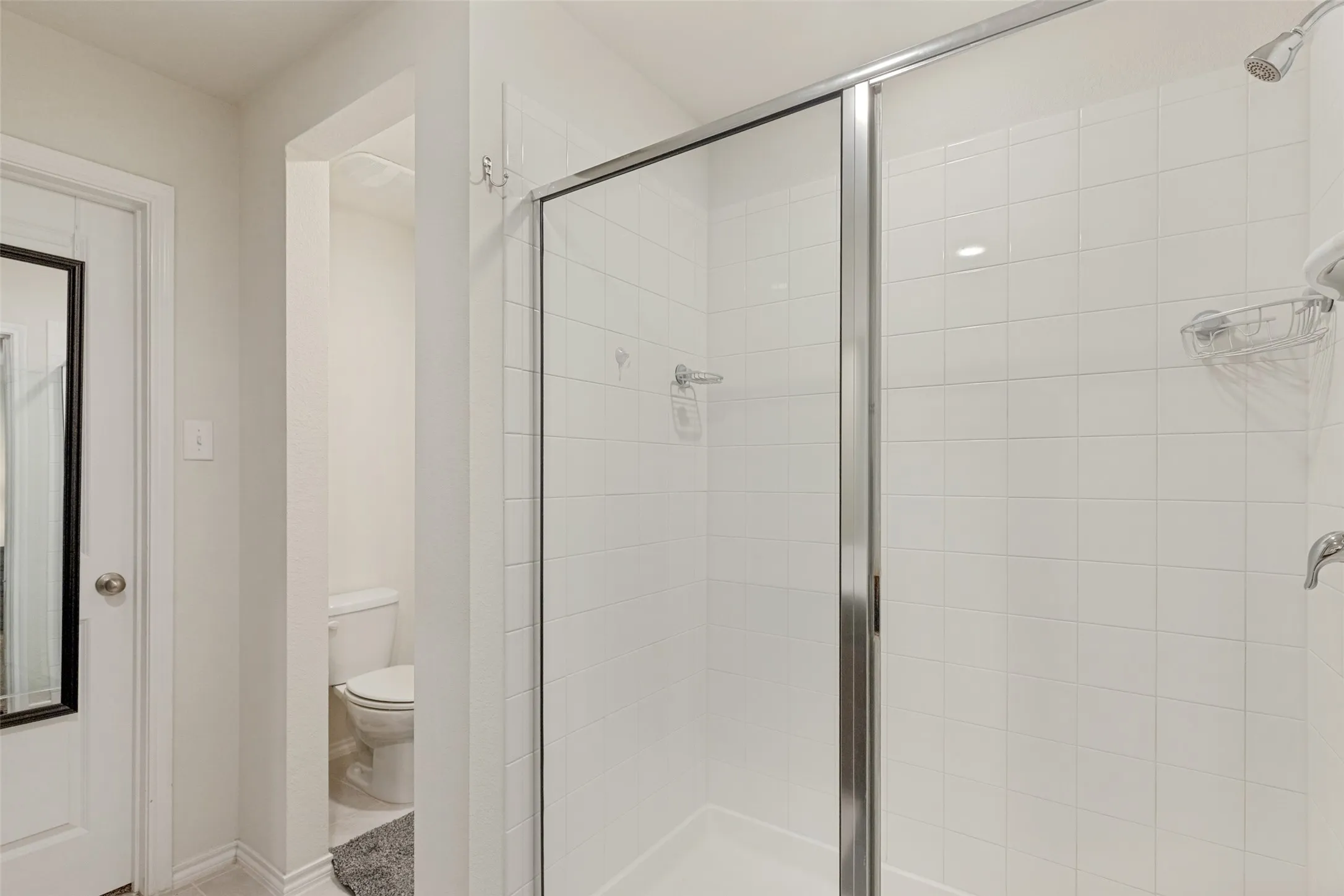 Enclosed shower with clear glass and polished chrome framing, white subway tile surround, and chrome shower fixtures
