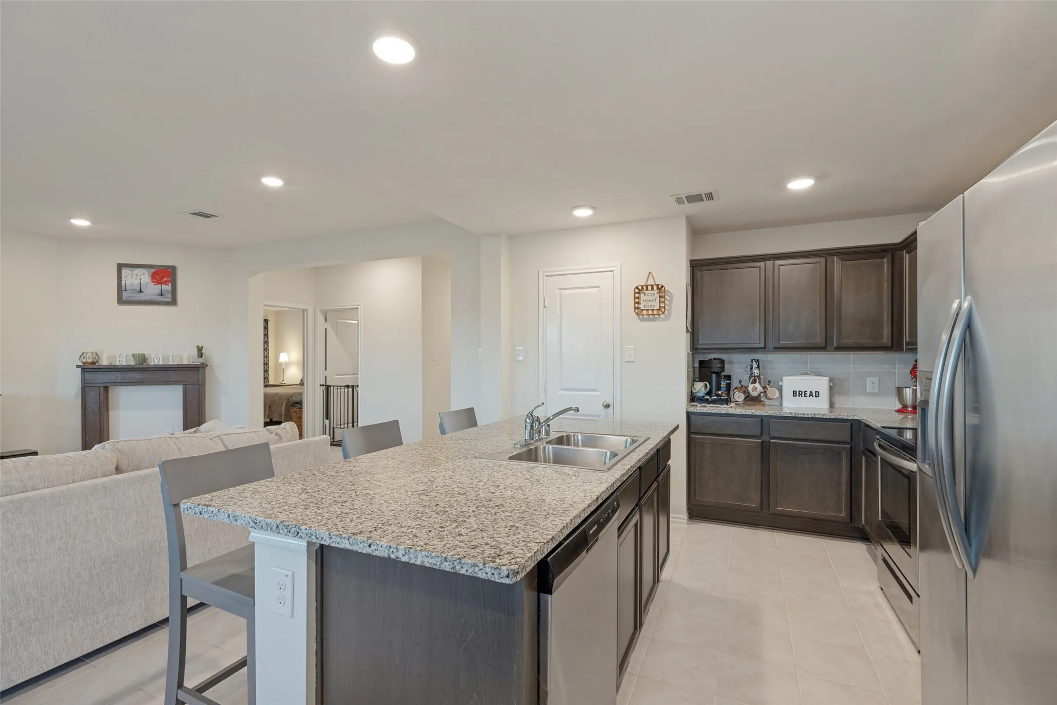 Kitchen featuring an expansive island with a granite countertop, dual basin sink, and stainless steel dishwasher