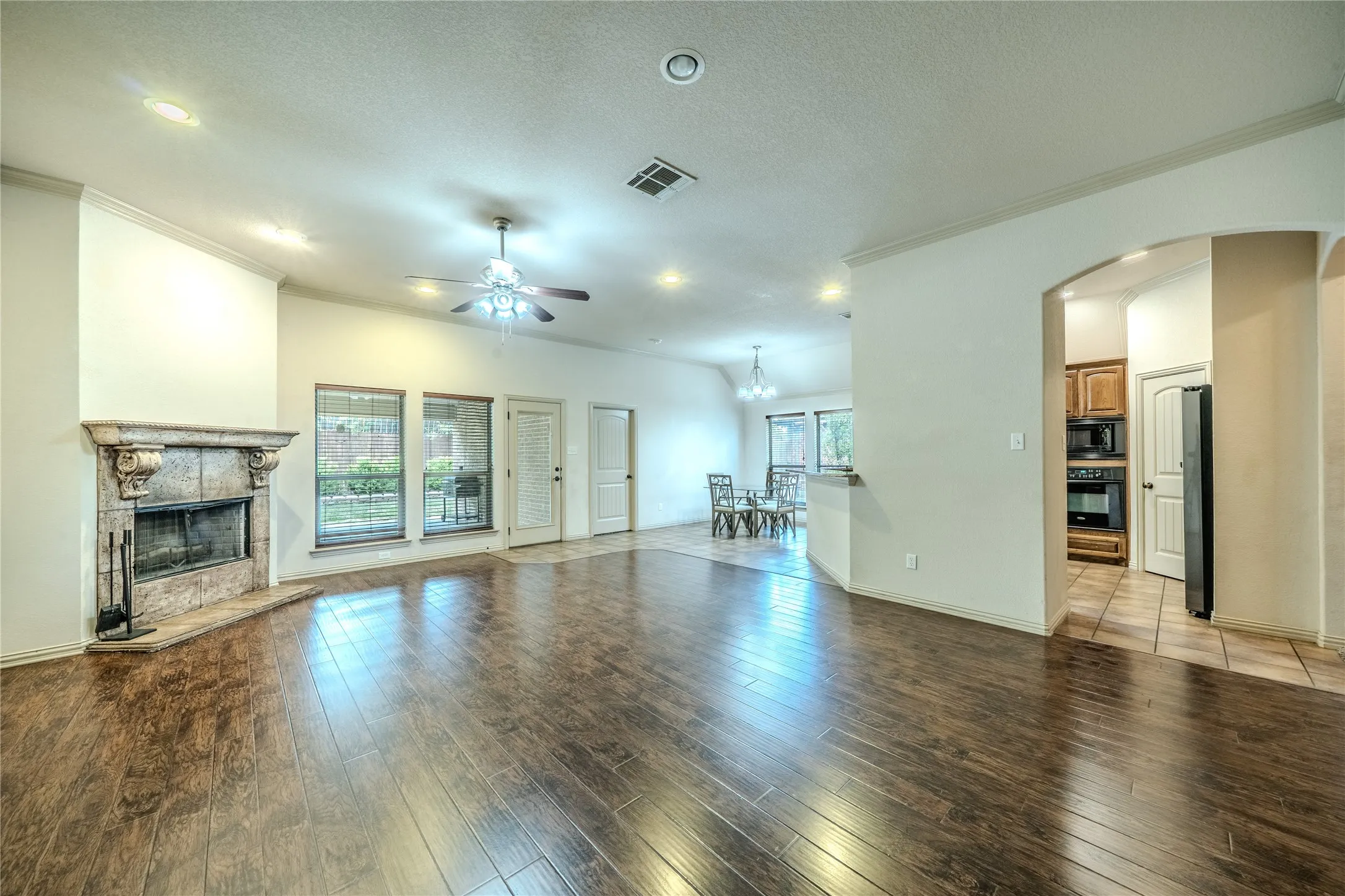 Living area showing fireplace and view of covered patio as well as open dining and kitchen.