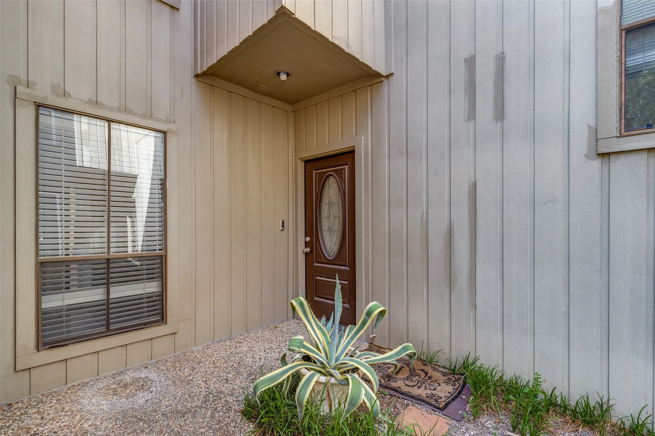 Recessed entry with overhead lighting, a decorative wood-finish entry door, and a multi-pane fixed window