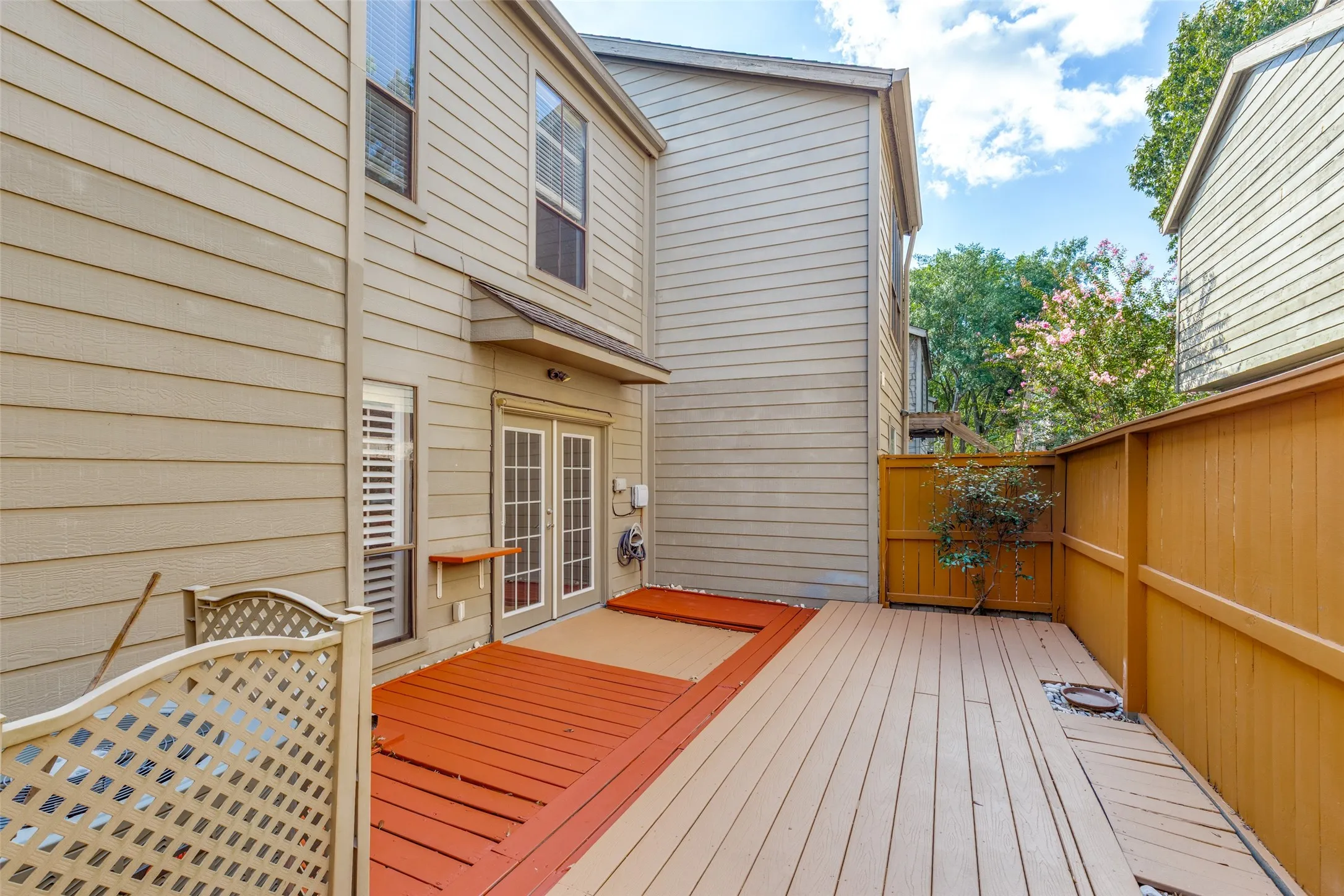 Expansive multi-level wood deck, privacy fencing, and double French doors