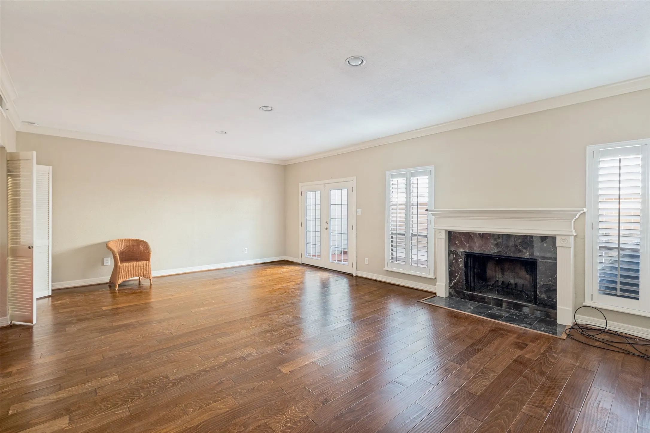 Wood-finish flooring, recessed lighting, and a fireplace with a stone surround and mantel