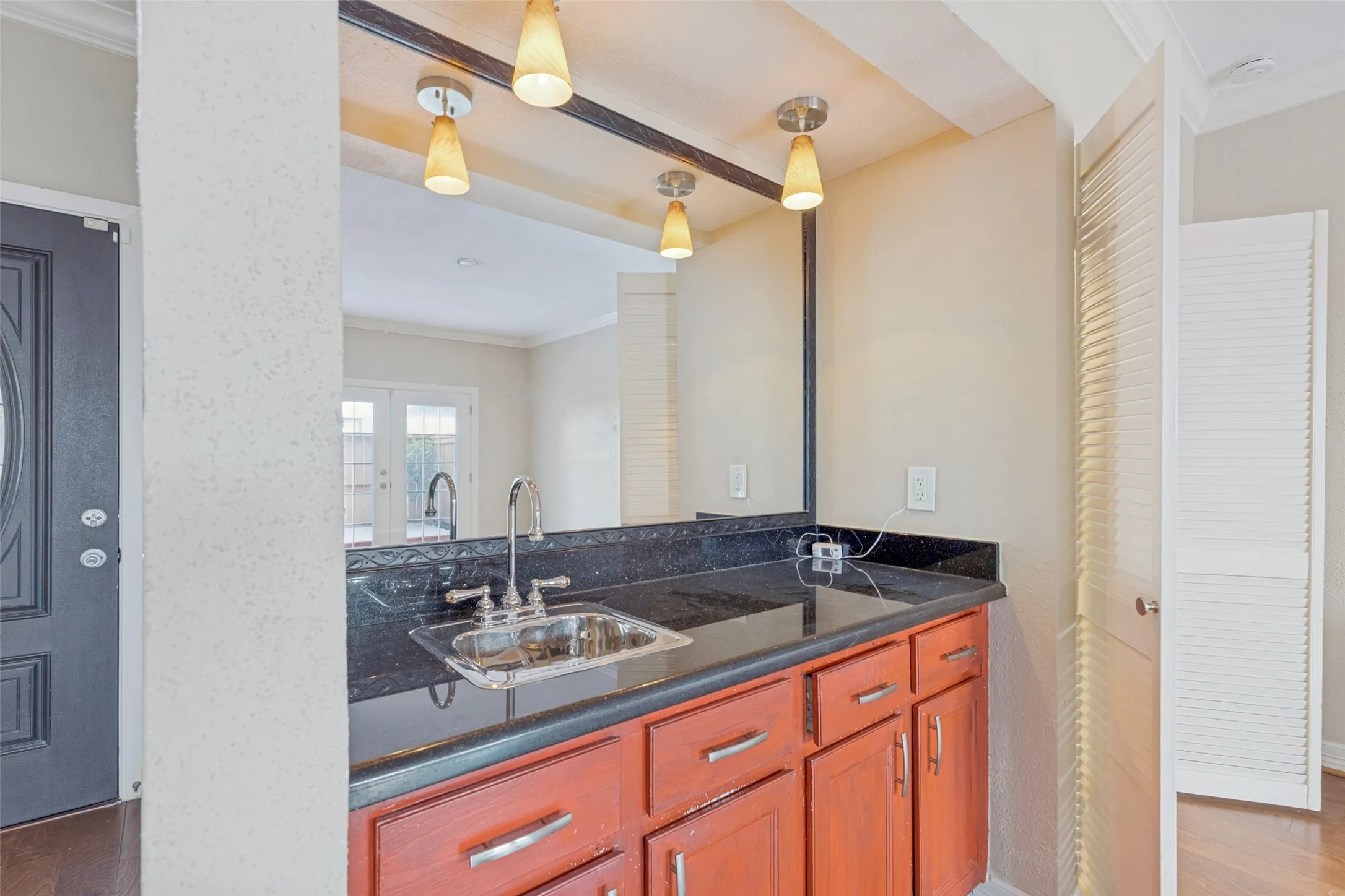 Built-in bar area featuring a stainless steel sink, dark countertop, and warm-toned cabinetry