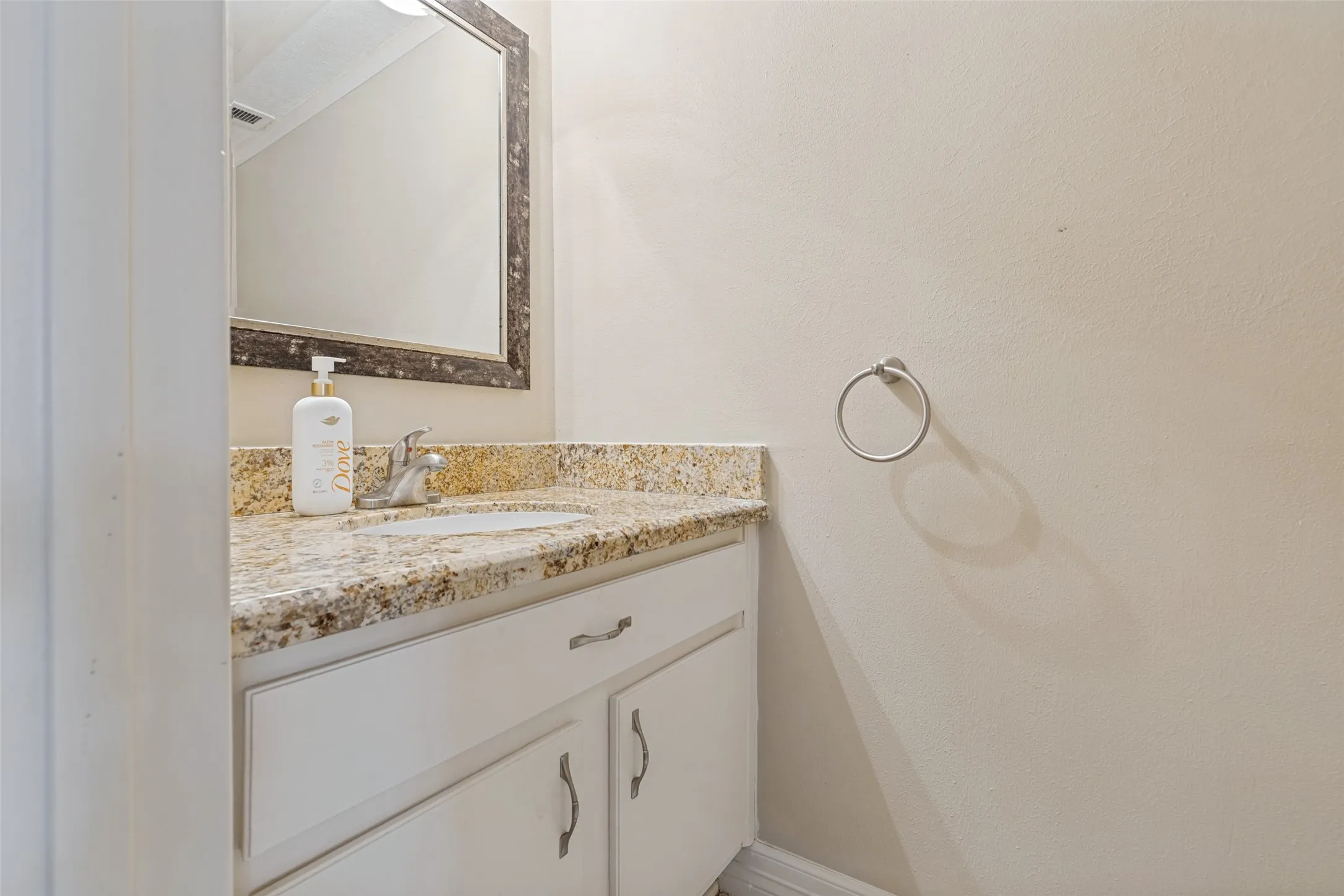 Vanity with a granite countertop, undermount sink, and chrome faucet