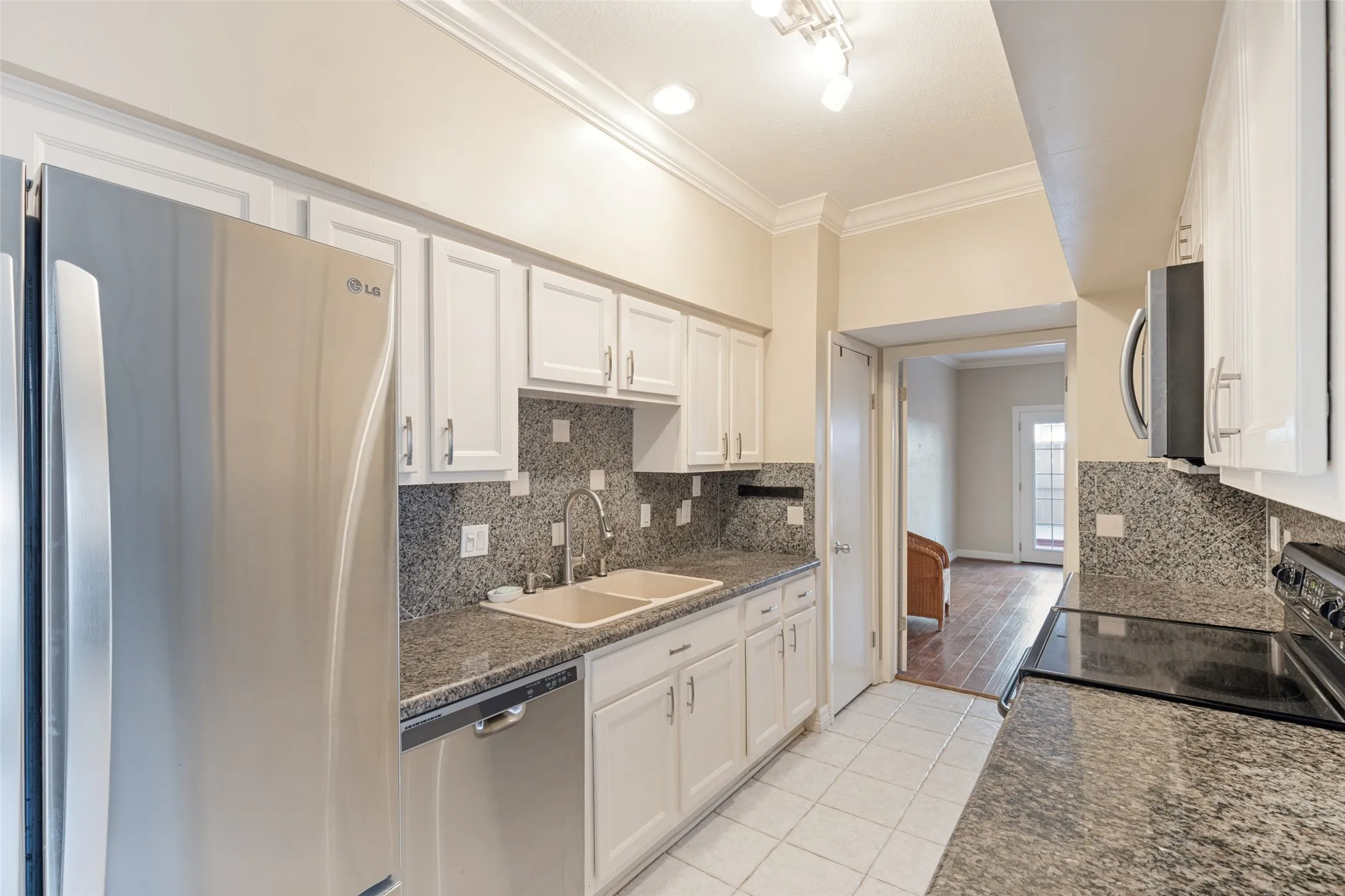 Kitchen featuring white cabinetry, dark stone countertops, stainless steel appliances, and a tile backsplash