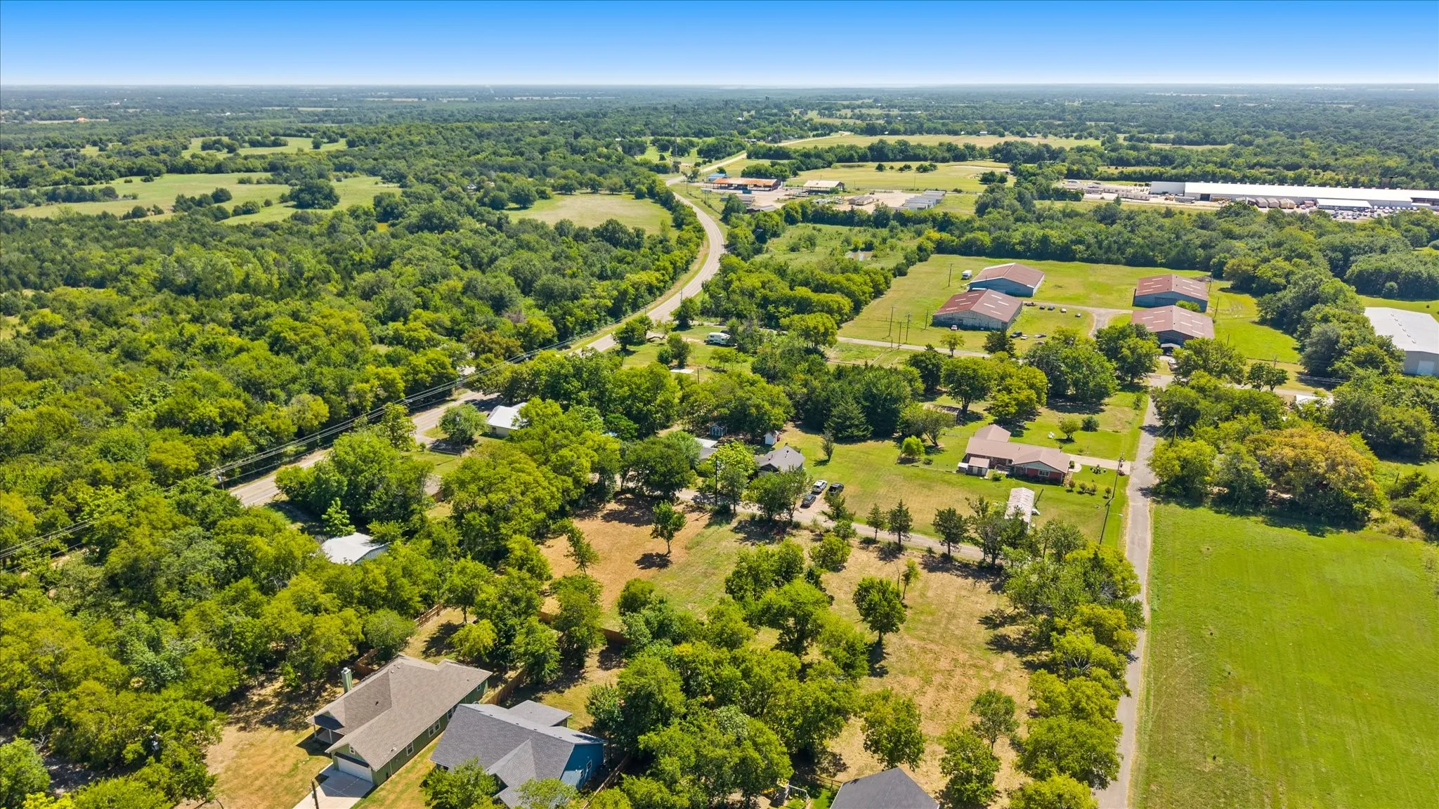 Expansive rural landscape featuring extensive tree coverage, open fields, and residential properties