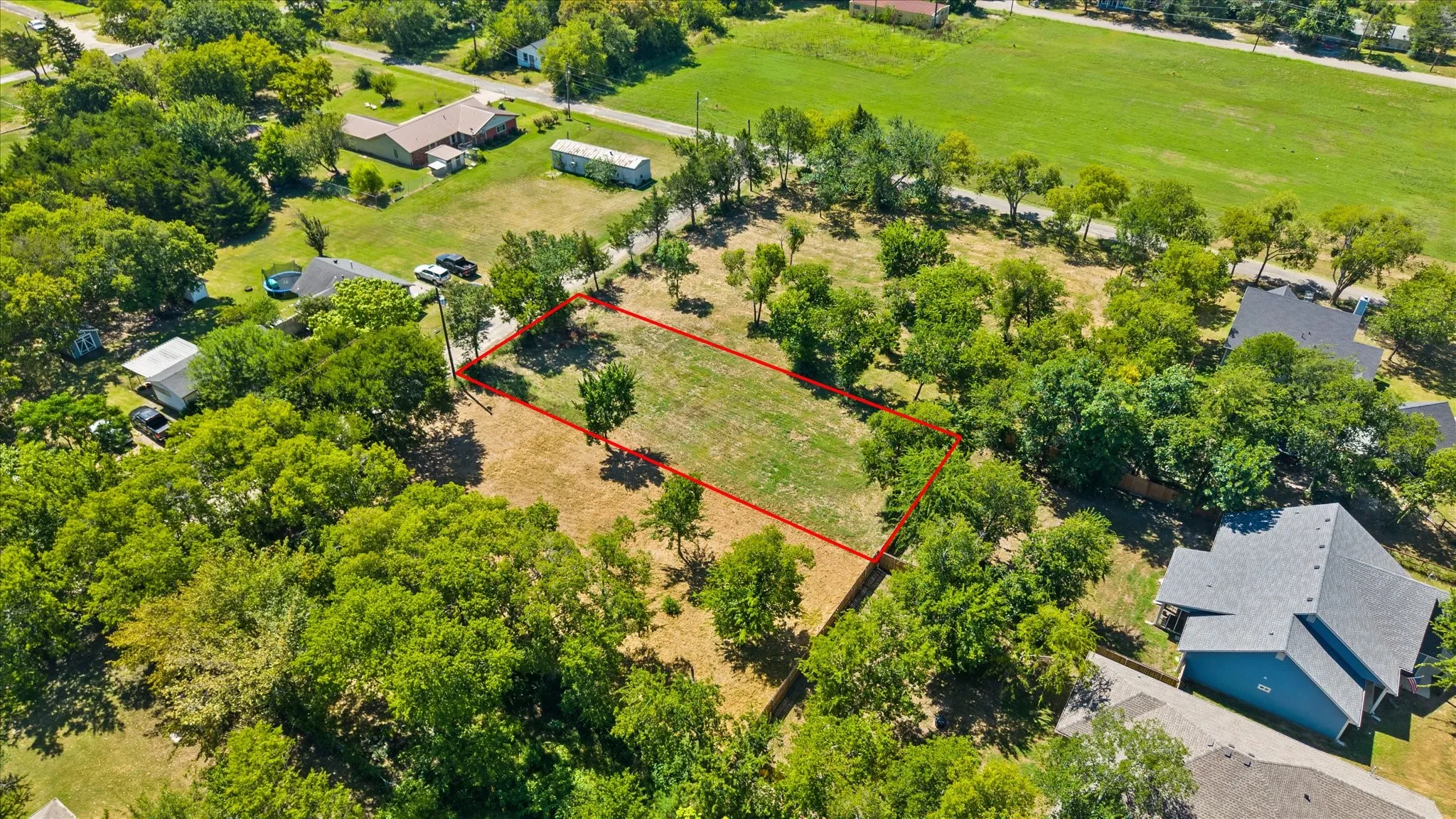 Expansive lot featuring a cleared building envelope, mature perimeter trees, and a surrounding green landscape