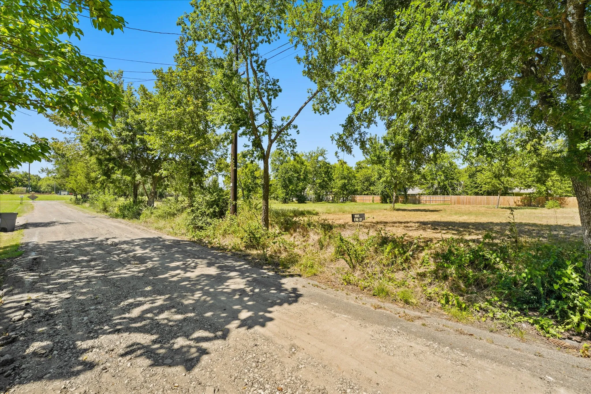 Gravel road with mature trees and a level lot