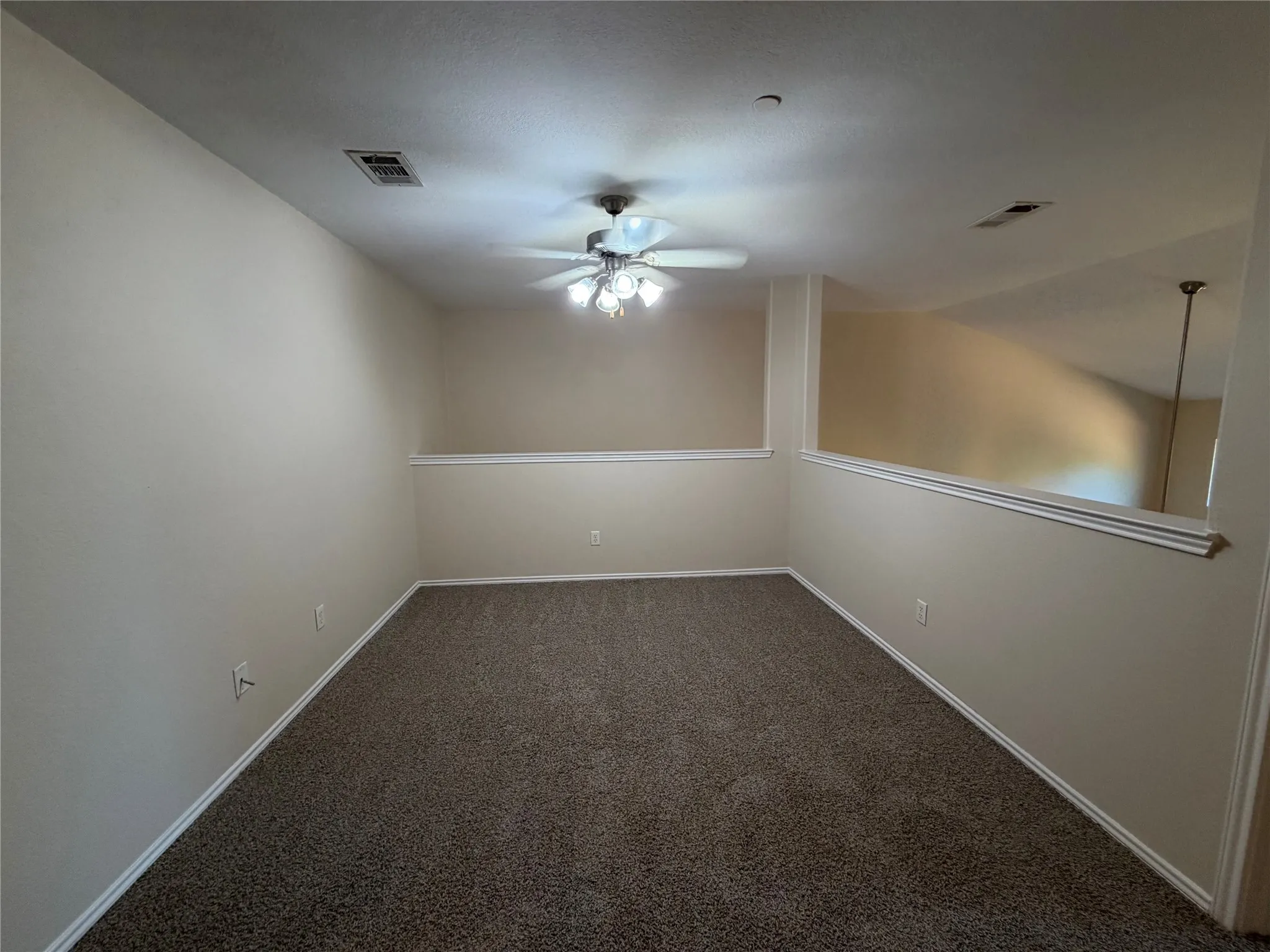 Carpeted room with a ceiling fan light fixture and a half-wall partition