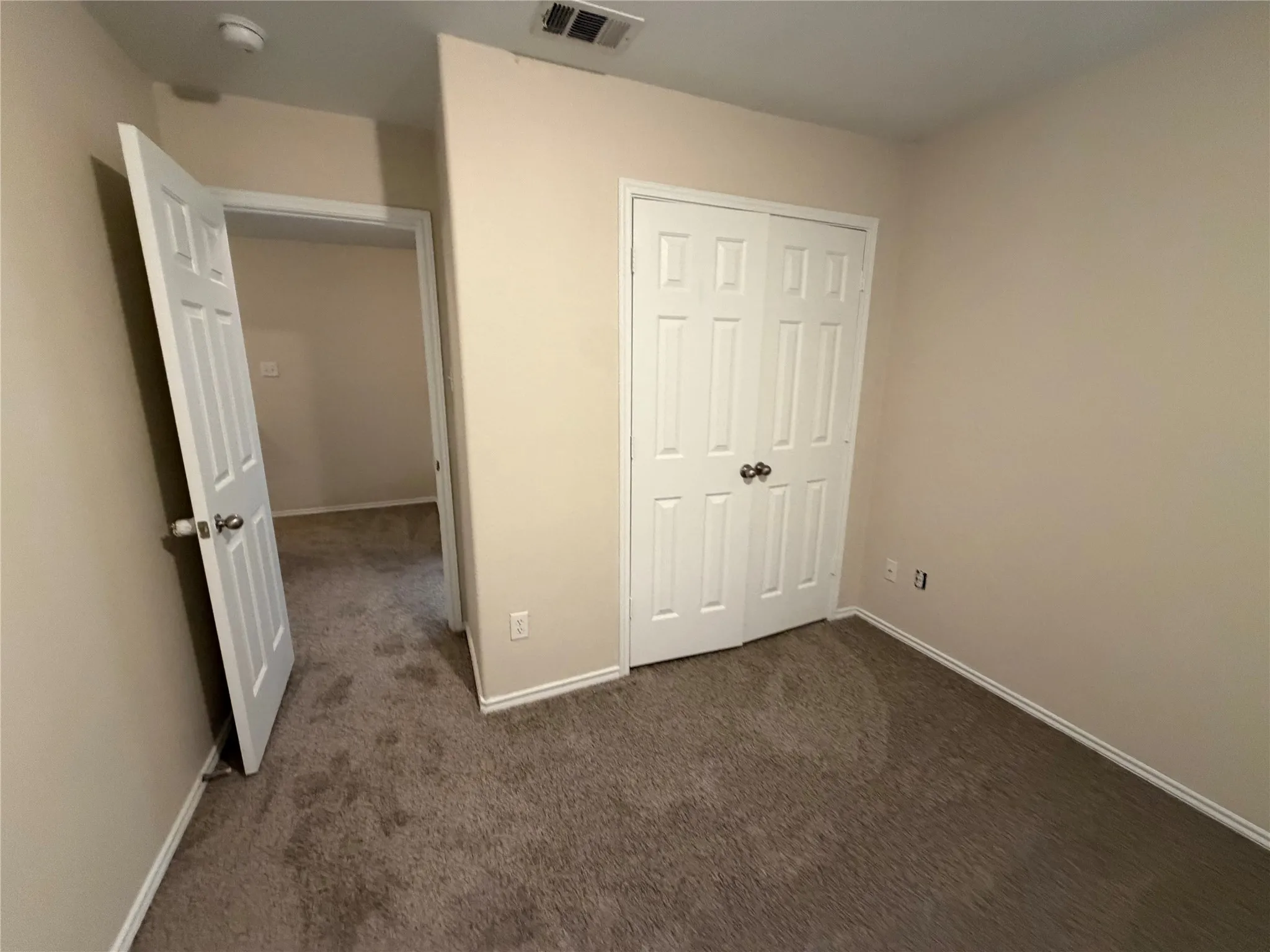 Neutral wall paint, textured carpeting, panel doors, and a bi-fold closet door