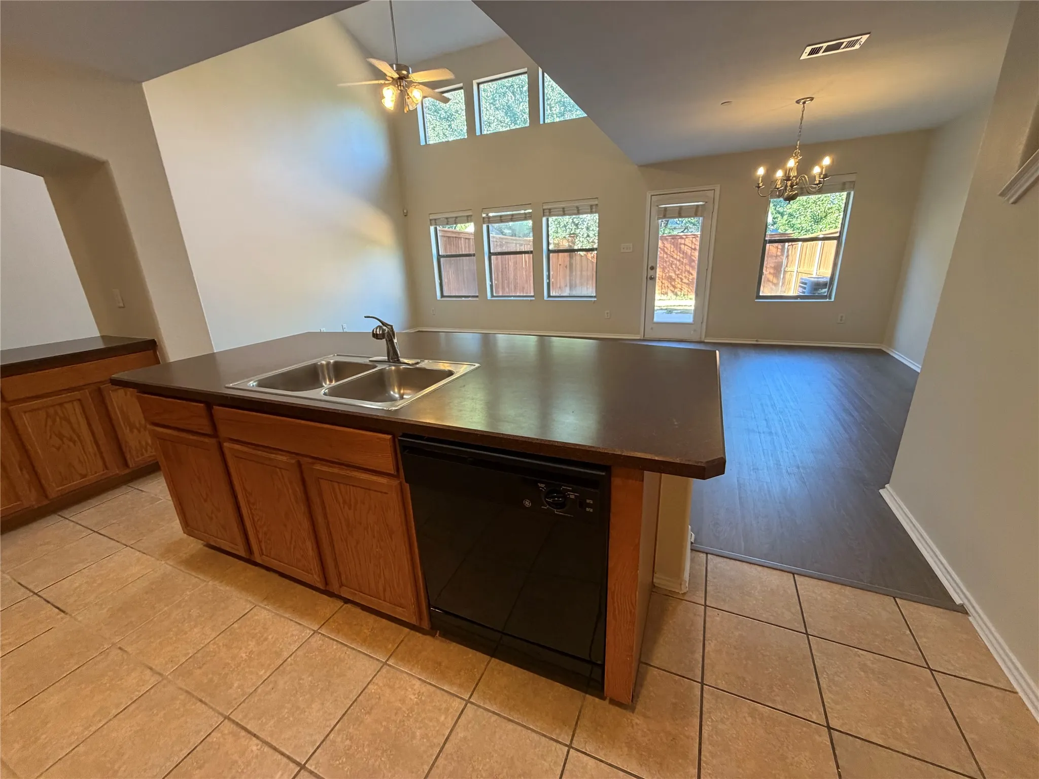 Kitchen island with a double basin sink, integrated dishwasher, and tile flooring